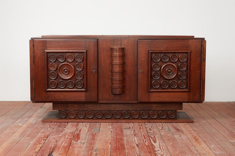 Incredible sideboard by Charles Dudouyt, France circa 1940's
Intricately carved circular pattern design on both doors and base of cabinet 
Rich patina to wood and wonderful overall craftsmanship 
Interior has open shelving with single drawer for