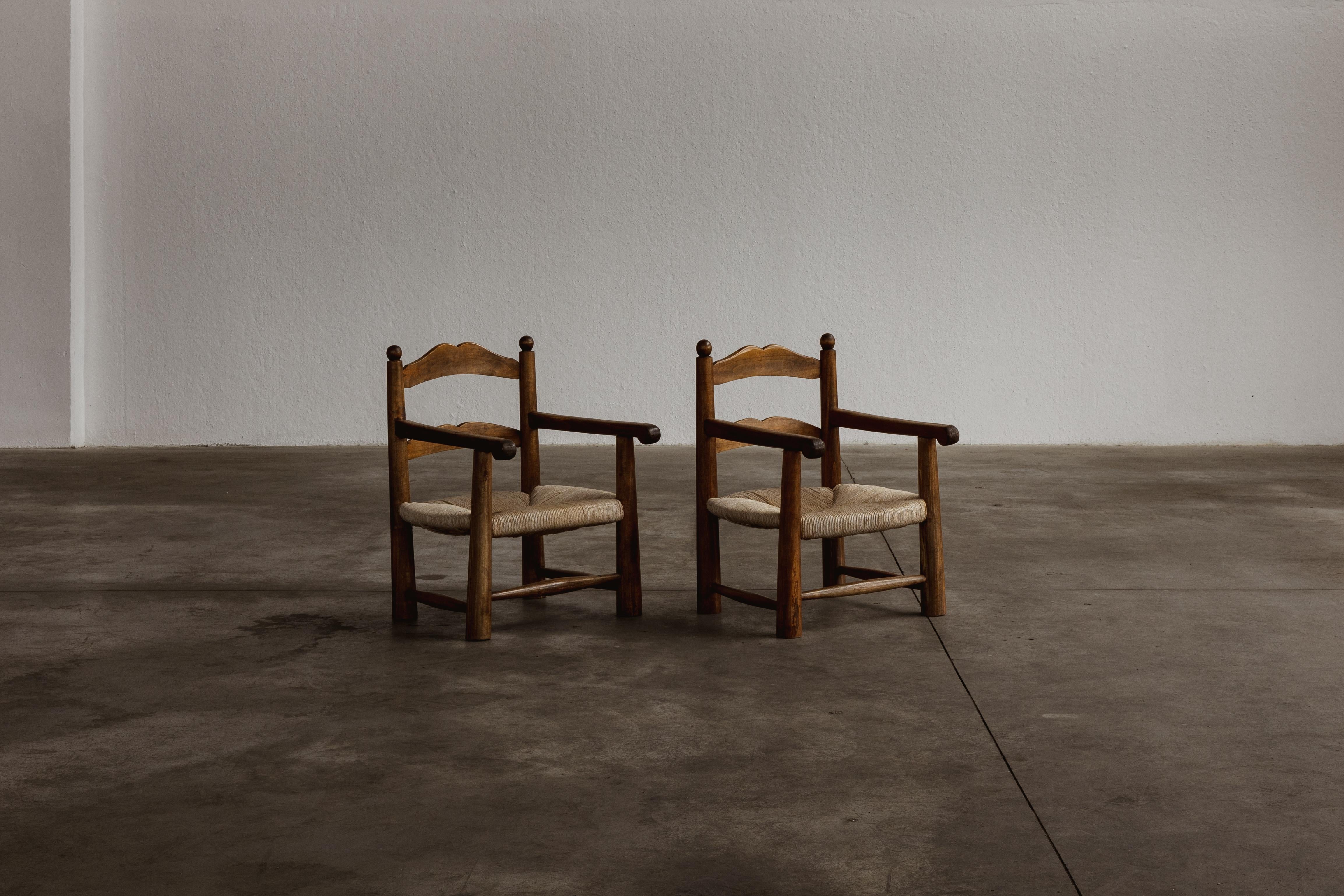 Charles Dudouyt easy chairs, straw and wood, France, 1940s, set of two.

Recalling the turned chair model, Charles Dudouyt created these carved chairs as 'fireside' chairs, hence the low seats. Using playful geometries and construction, he crafted