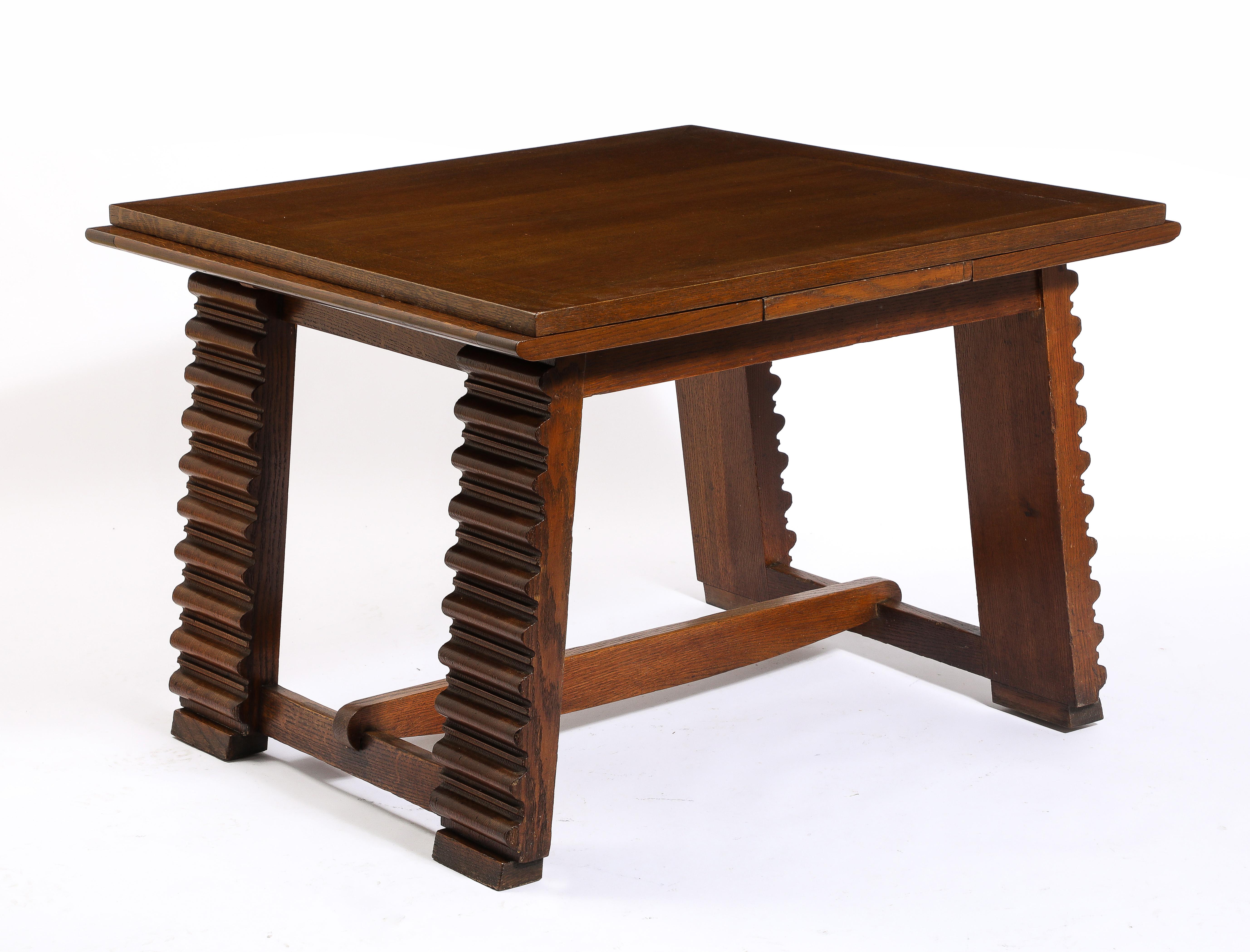 Striking center table in oak with intricately carved legs linked by a semi curved stretcher, the cleverly designed top deploys from 41” to 75” by simply pulling the leaves that subtly protrude on each ends.
