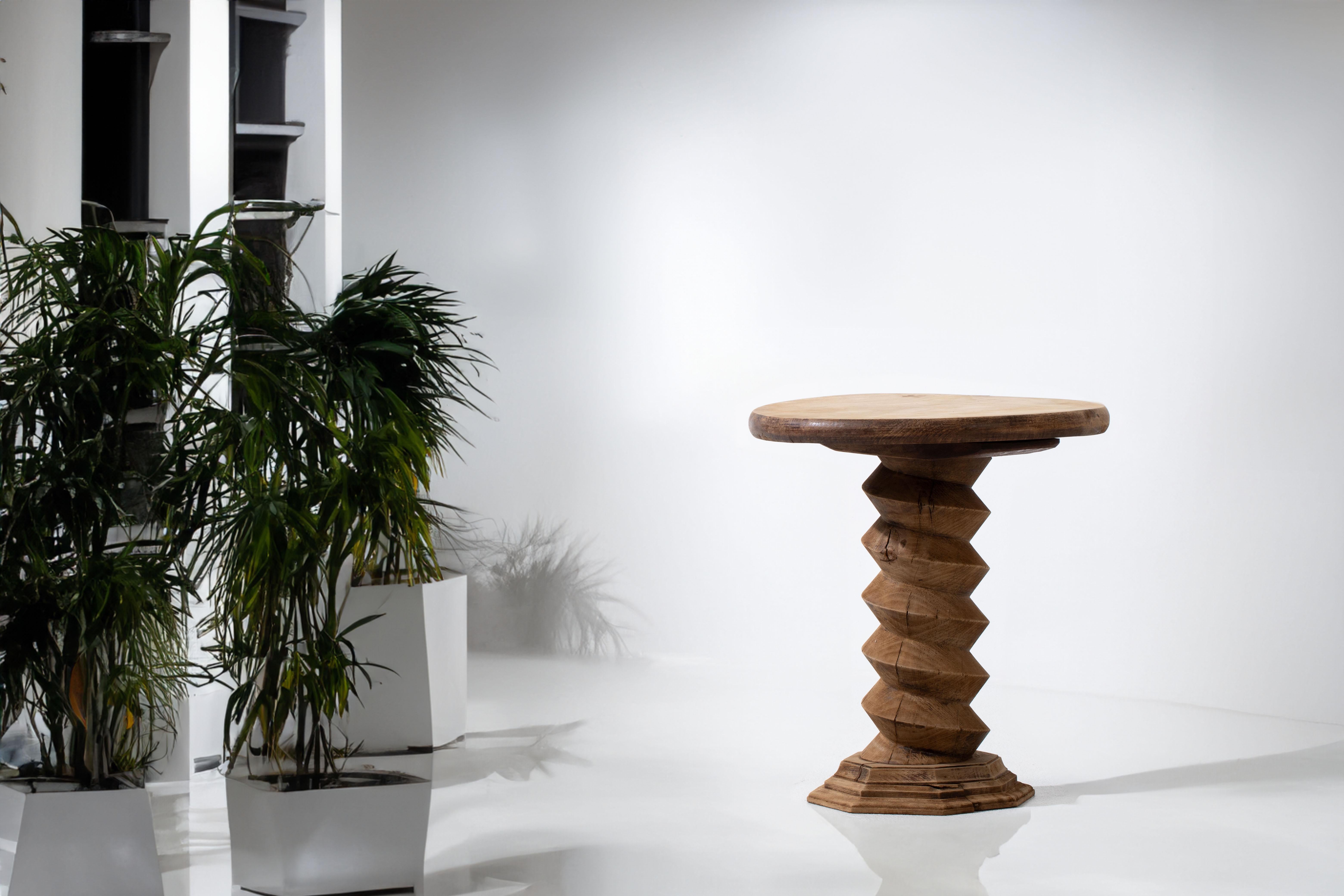 Introducing a captivating French vintage end table or gueridon, exquisitely inspired by the iconic style of renowned designer Charles Dudouyt. Crafted from natural oak, this charming piece showcases Dudouyt's signature wine press screw leg design, a