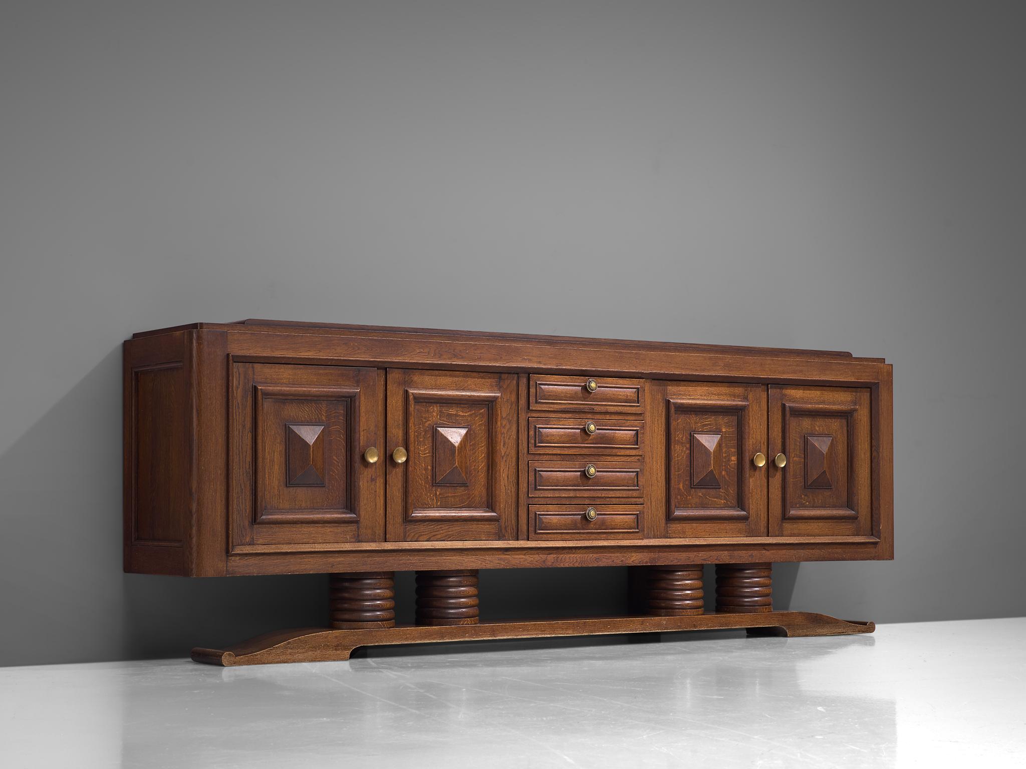 Charles Dudouyt, sideboard, oak and brass, France, 1930s. 

Sturdy credenza in oak in an exceptional size with graphical door panels. This four-door sideboard is equipped with several shelves and drawers which provide plenty of storage space.