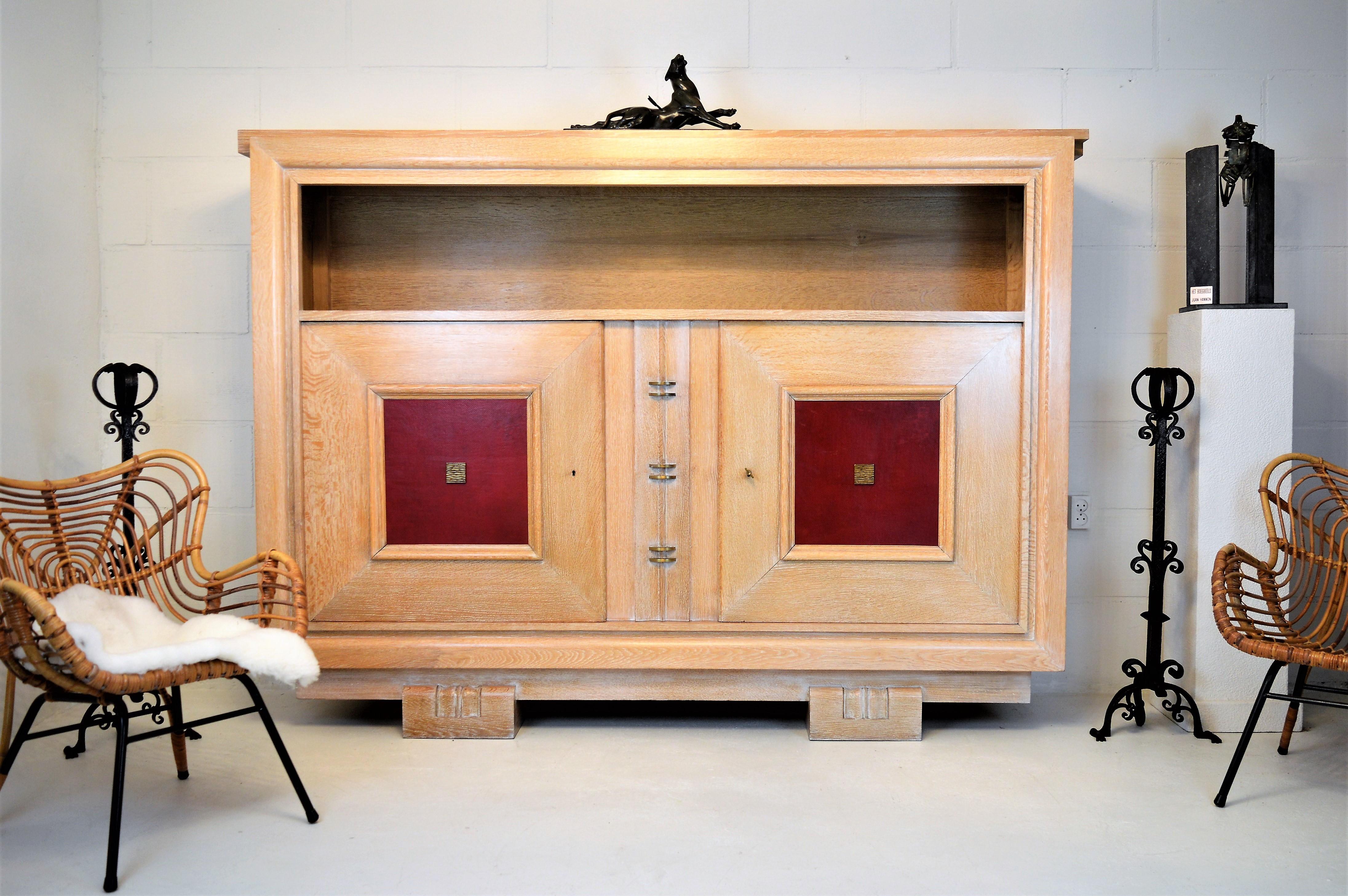 Very luxury version of a Charles Dudouyt cabinet . This cabinet with doorpanels in red leather and stylish applications in bronze, has a secret space in the middle as shown in the pictures. It cannot be opened if the left door is closed.
This