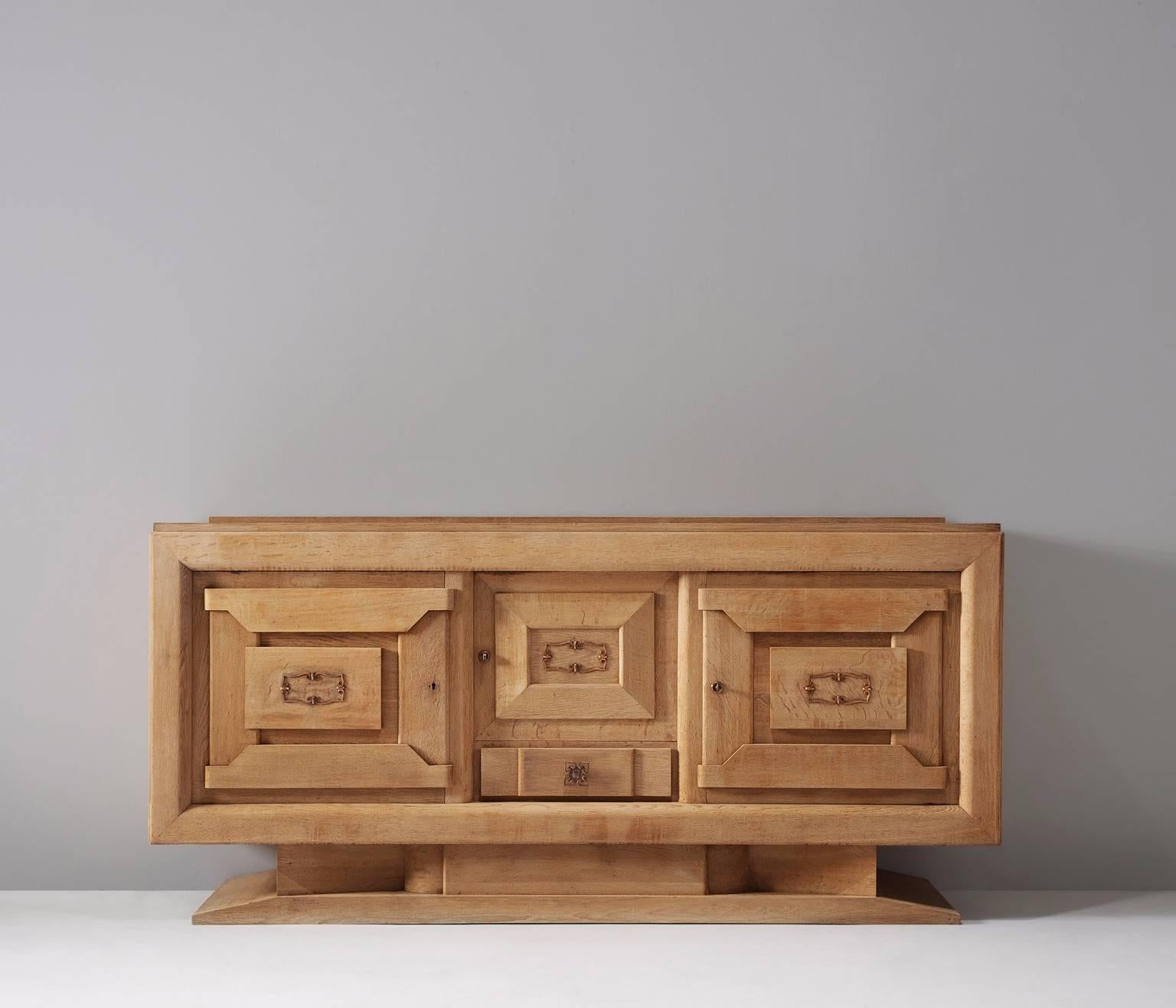 Credenza in oak, by Charles Dudouyt, France, 1930s. 

French Art Deco oak credenza designed by the decorator Charles Dudouyt. The solid wooden frame gives this sideboard a sturdy character. The door panels show an interesting pattern of solid