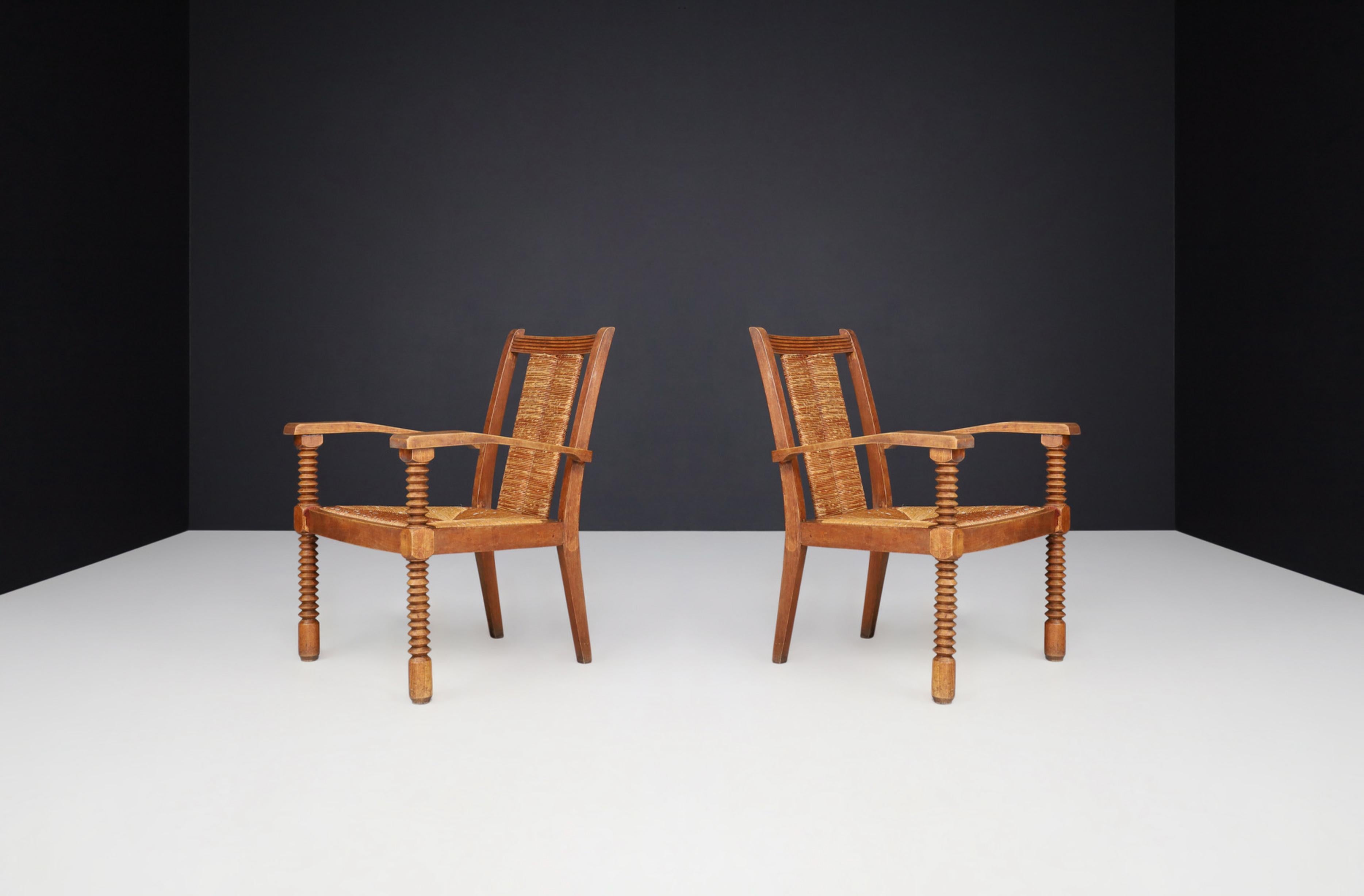 Charles Dudouyt Patinated Oak and Rush Armchairs, France 1940s

These fine armchairs were designed by the renowned French furniture maker Charles Dudouyt in the 1940s and are exceptional. These armchairs feature Dudouyt's iconic corkscrew-shaped