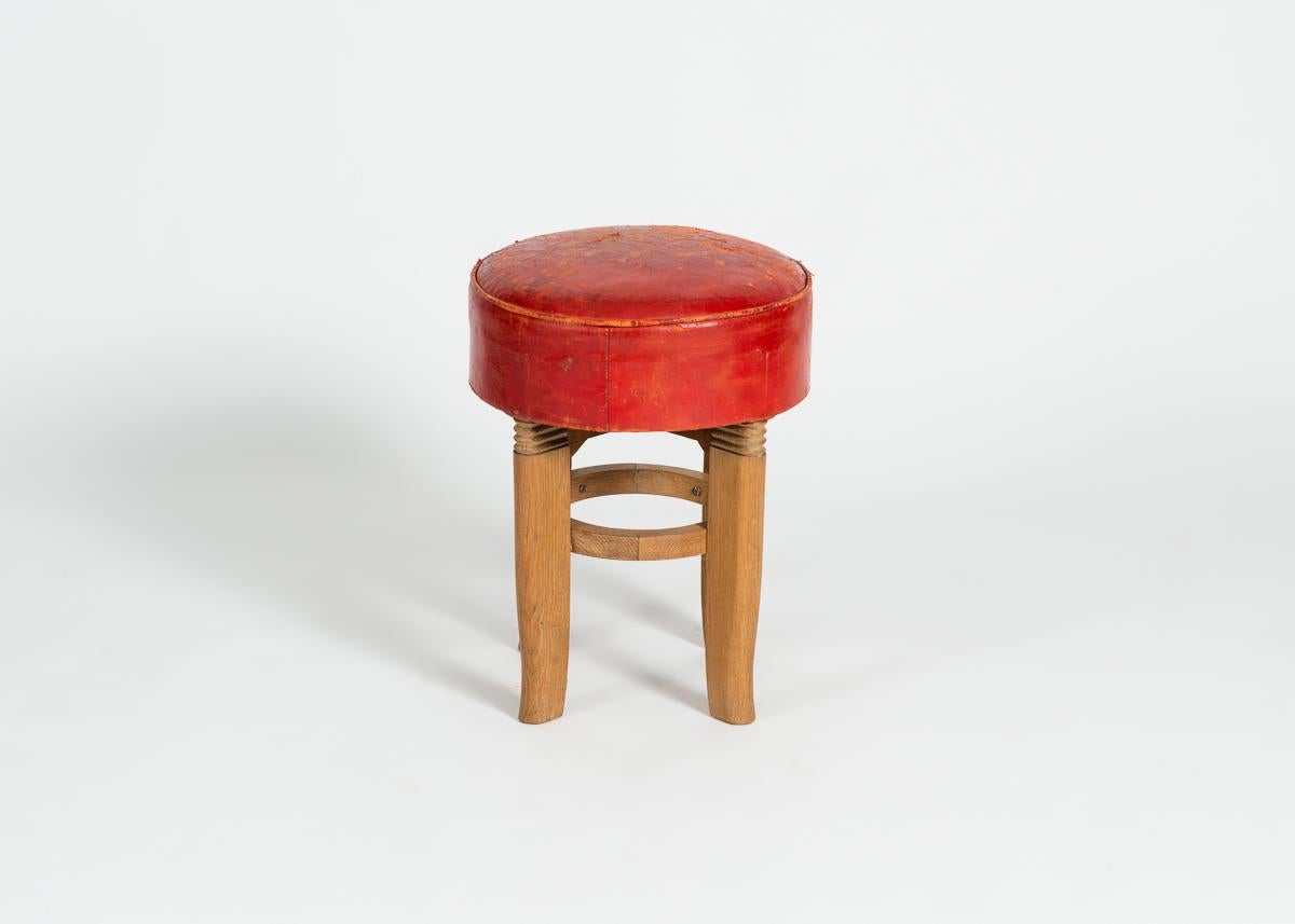 Round polished-oak and red leather stool by French designer Charles Dudouyt.