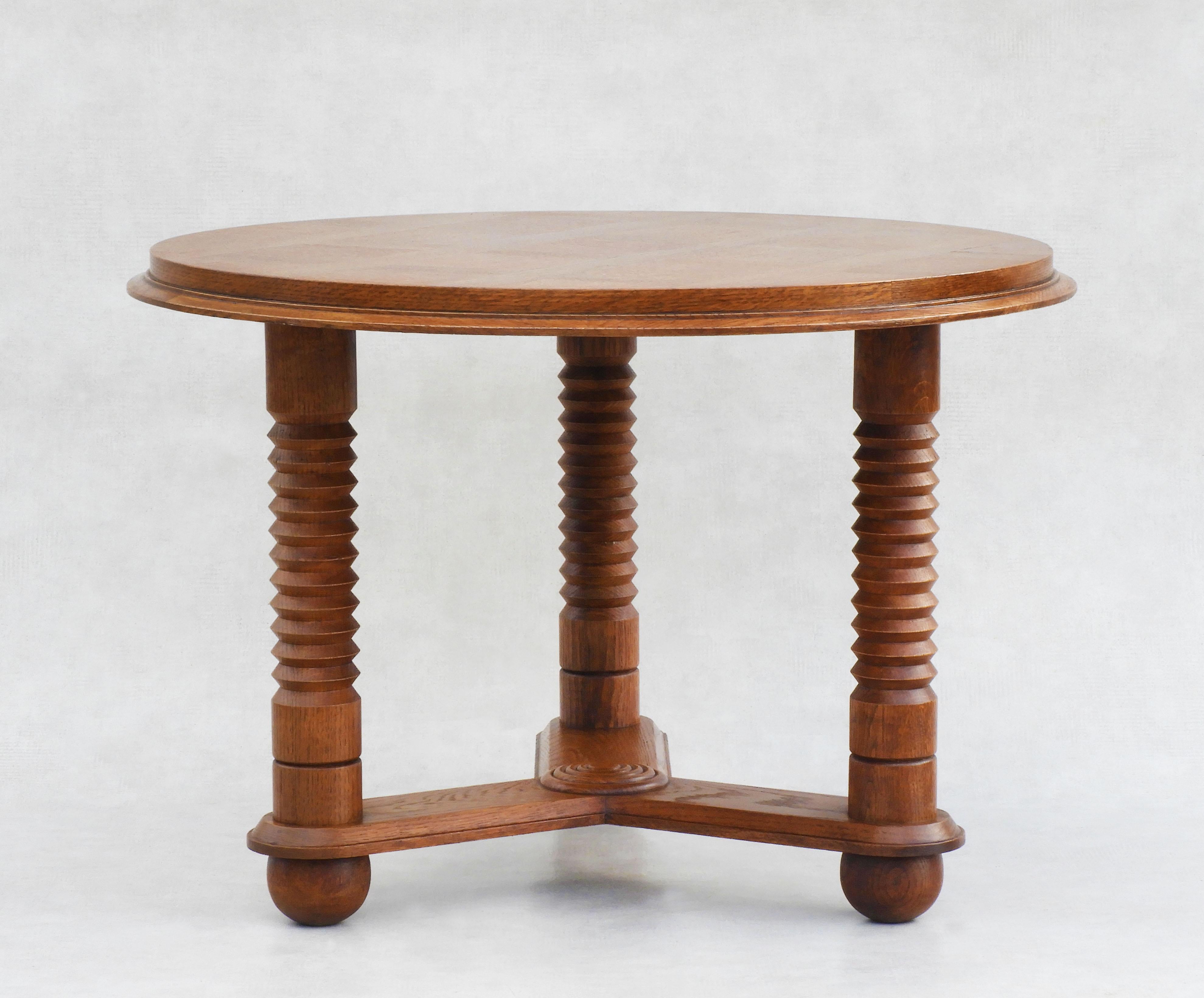 Stylish round oak coffee table in the style of Charles Dudouyt/Atelier Gentilhommière C1950.           
Great design and good craftsmanship with signature-turned columns, circular geometric detailing and ball feet. This nicely proportioned table