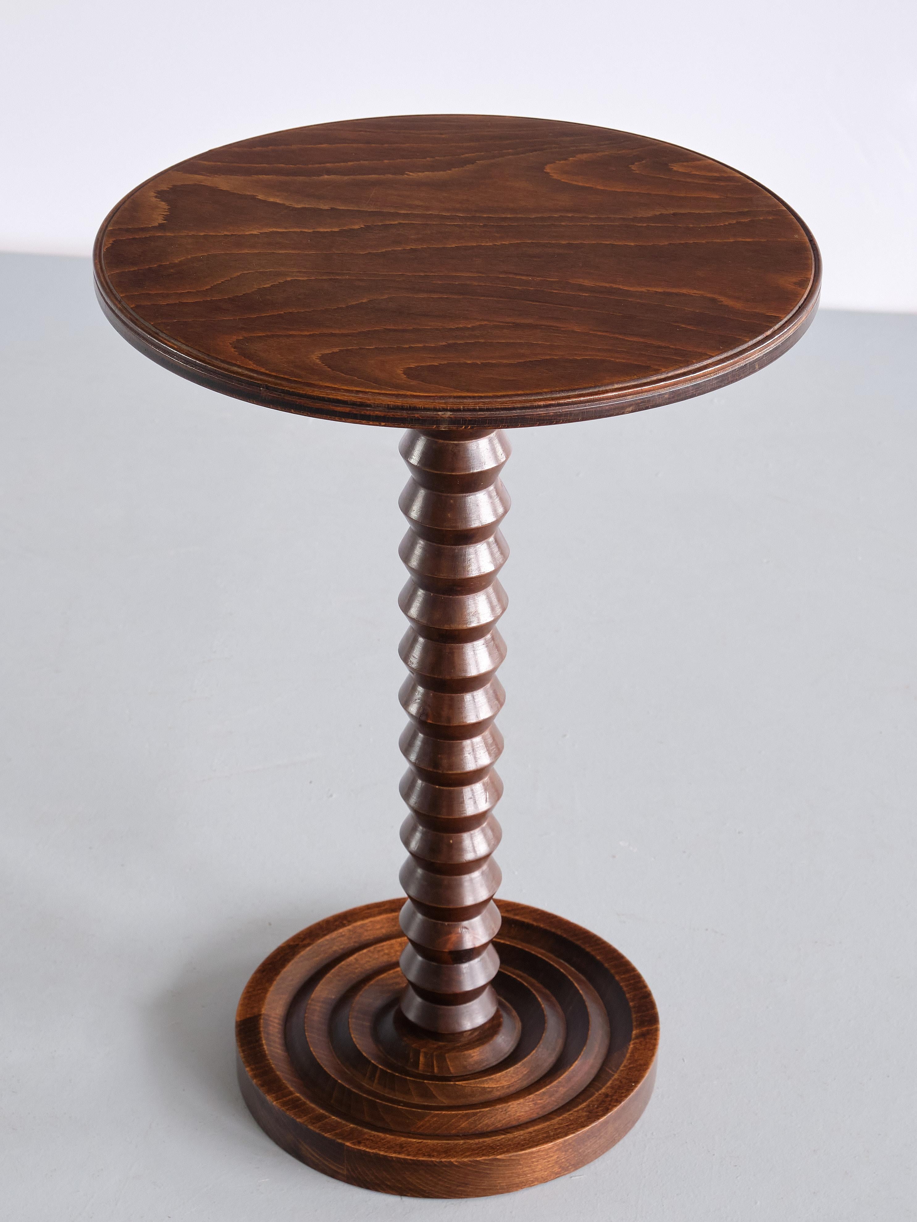 This rare side table was designed by Charles Dudouyt and produced in France in the late 1940s. The round top in solid dark stained oak with a rounded edge. The top with a visually attractive, distinct wood grain.The striking centred column is in