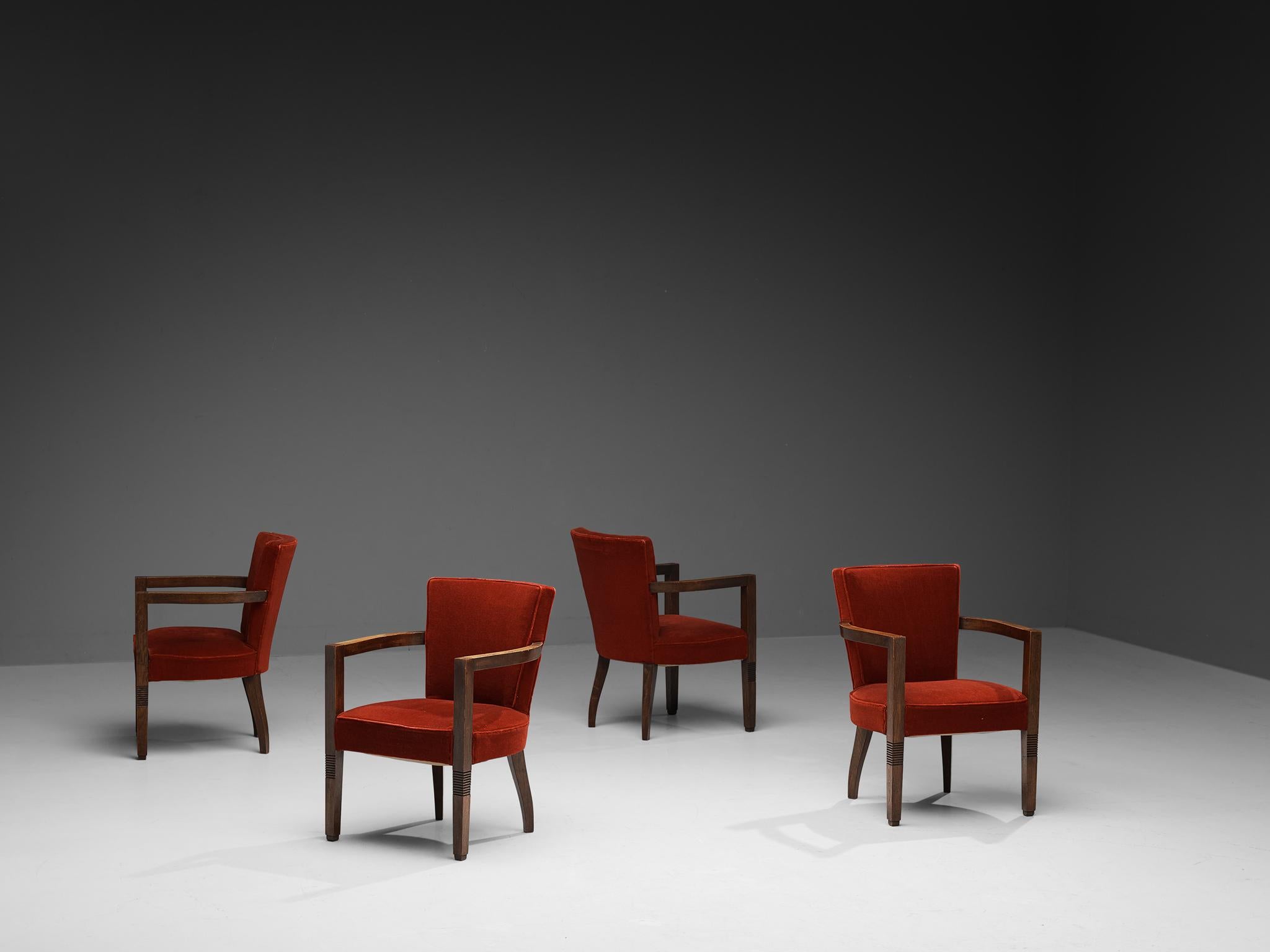 Charles Dudouyt, set of four armchairs, red velvet, stained oak, France, 1940s. 

This set of four Art Deco dining or armchairs is upholstered with deep red velvet fabric. The frame is made of solid stained oak and features tapered, carved legs. The