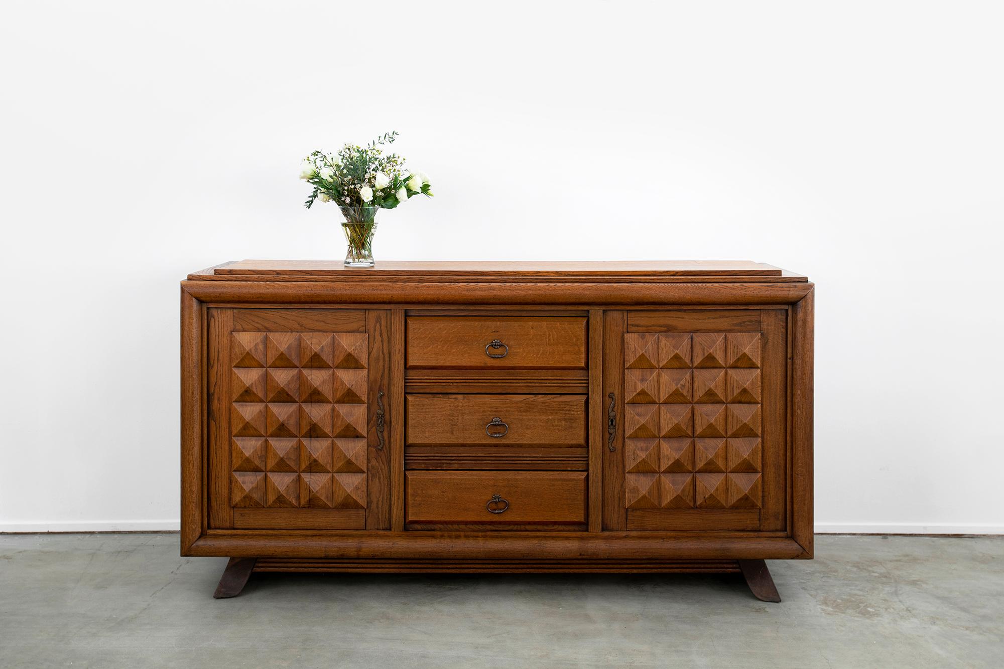 Large scale 1930s French oak cabinet designed by Charles Dudouyt. 
Intricately carved detail with plenty of storage - 2 separate cupboards doors that open with shelving inside. 
3 drawers in center panel 
Recessed angled legs 
Gorgeous patina to