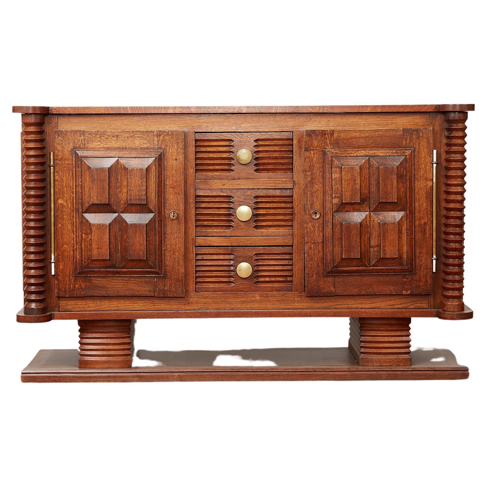 Charles Dudouyt sideboard in oak with carved corkscrew cylinder design throughout. 
Pedestal platform base with 3 carved center drawer
Original brass hardware and key for doors - which open to shelving for storage. 
Wonderful scale and patina to