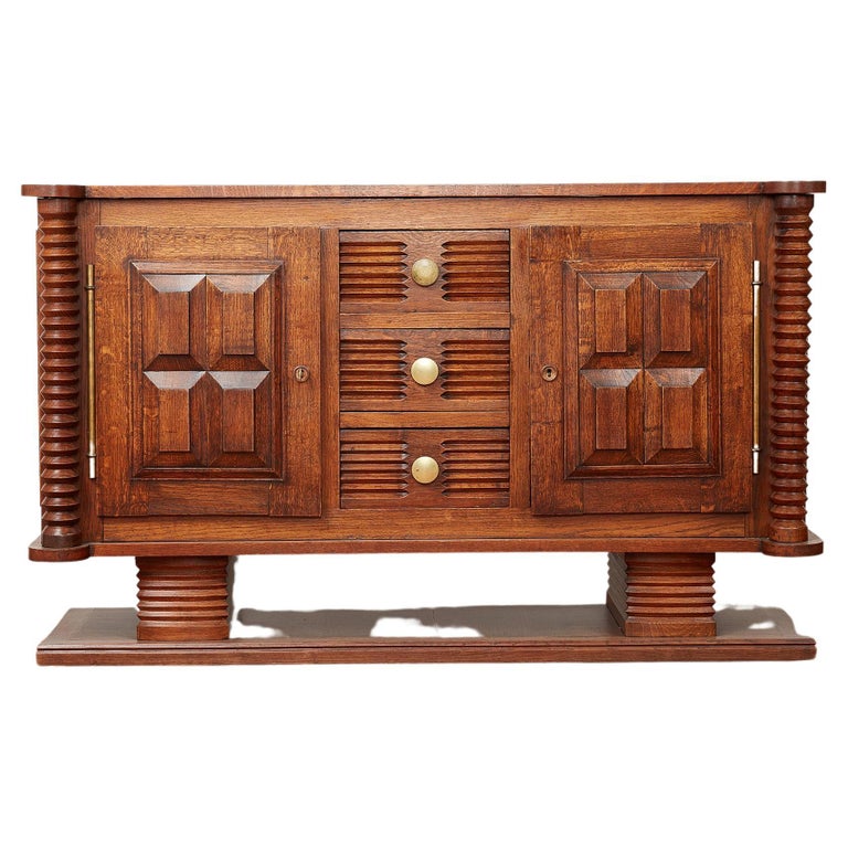 Charles Dudouyt sideboard in oak with carved corkscrew cylinder design throughout. 
Pedestal platform base with 3 carved center drawer
Original brass hardware and key for doors - which open to shelving for storage. 
Wonderful scale and patina to