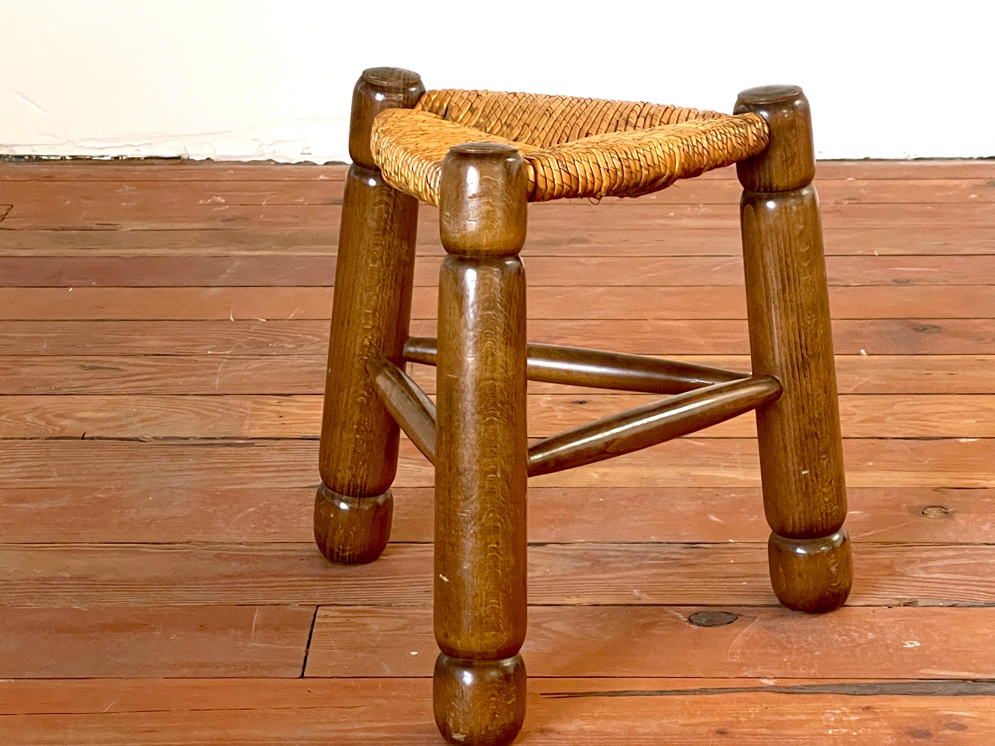 Petite chunky triangle shaped stool with carved oak legs and straw seat. 
In the style of Charles Dudouyyt.