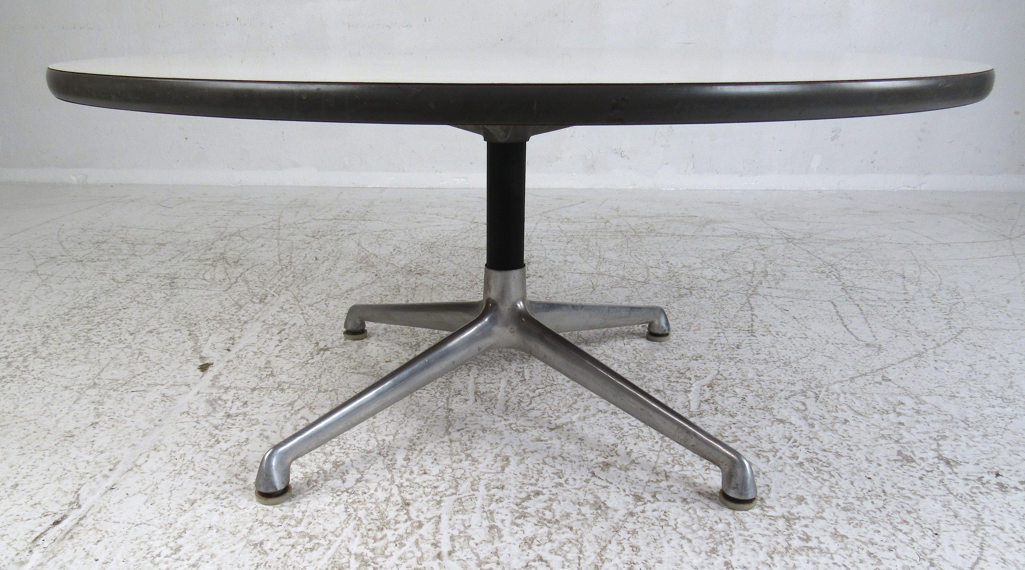 Cette table basse de style moderne du milieu du siècle est dotée d'un plateau en stratifié blanc avec une garniture en caoutchouc noir et soutenue par une base en aluminium. L'autocollant original Eames for Herman Miller est apposé sur la face