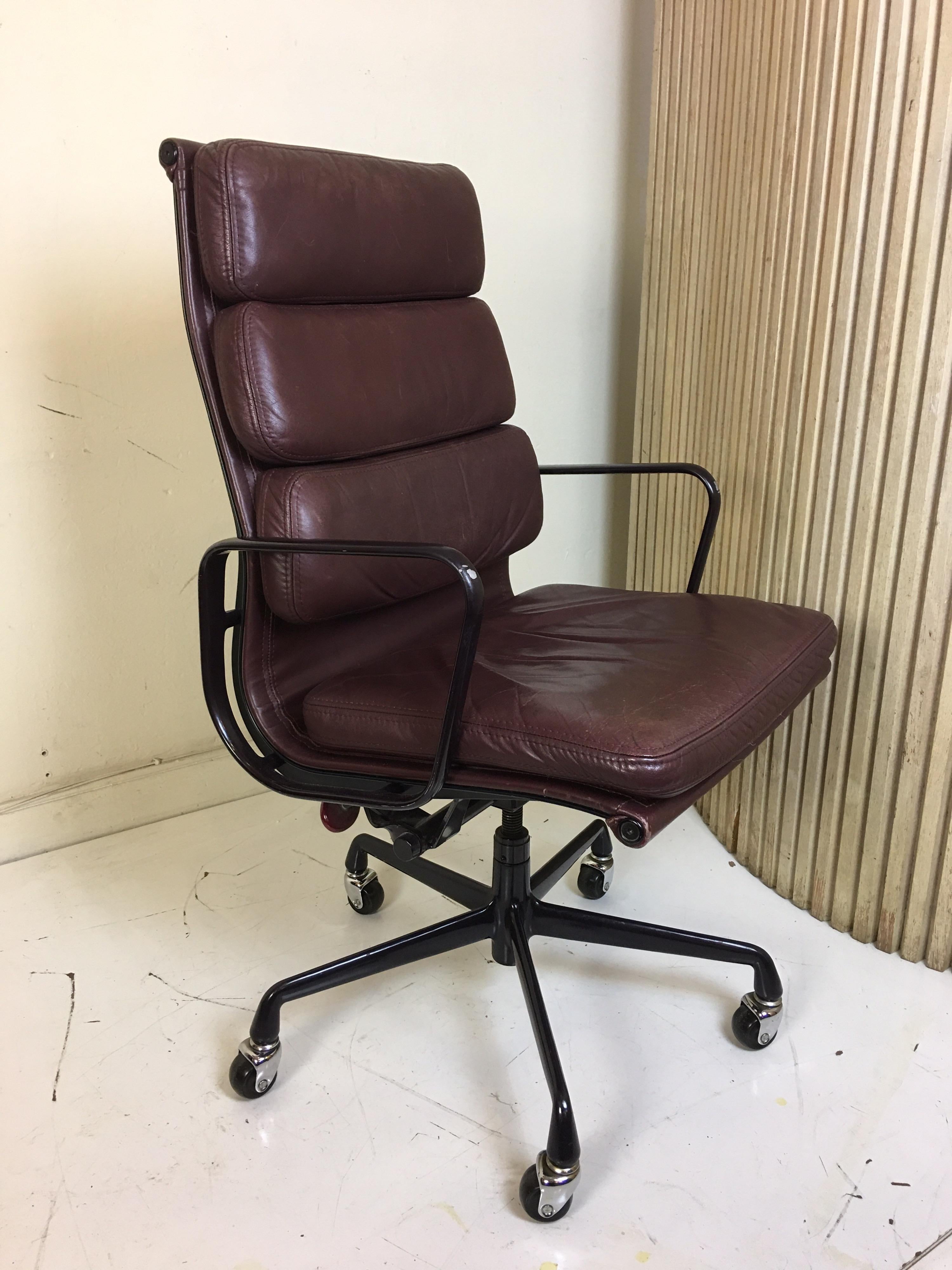 Charles Eames for Herman Miller executive leather soft pad chair in a deep maroon leather. Frame appears black but is a very deep eggplant color. Leather shows a nice amount of Patina with no rips or tears. Chair is dated 1989. Front of each arm has