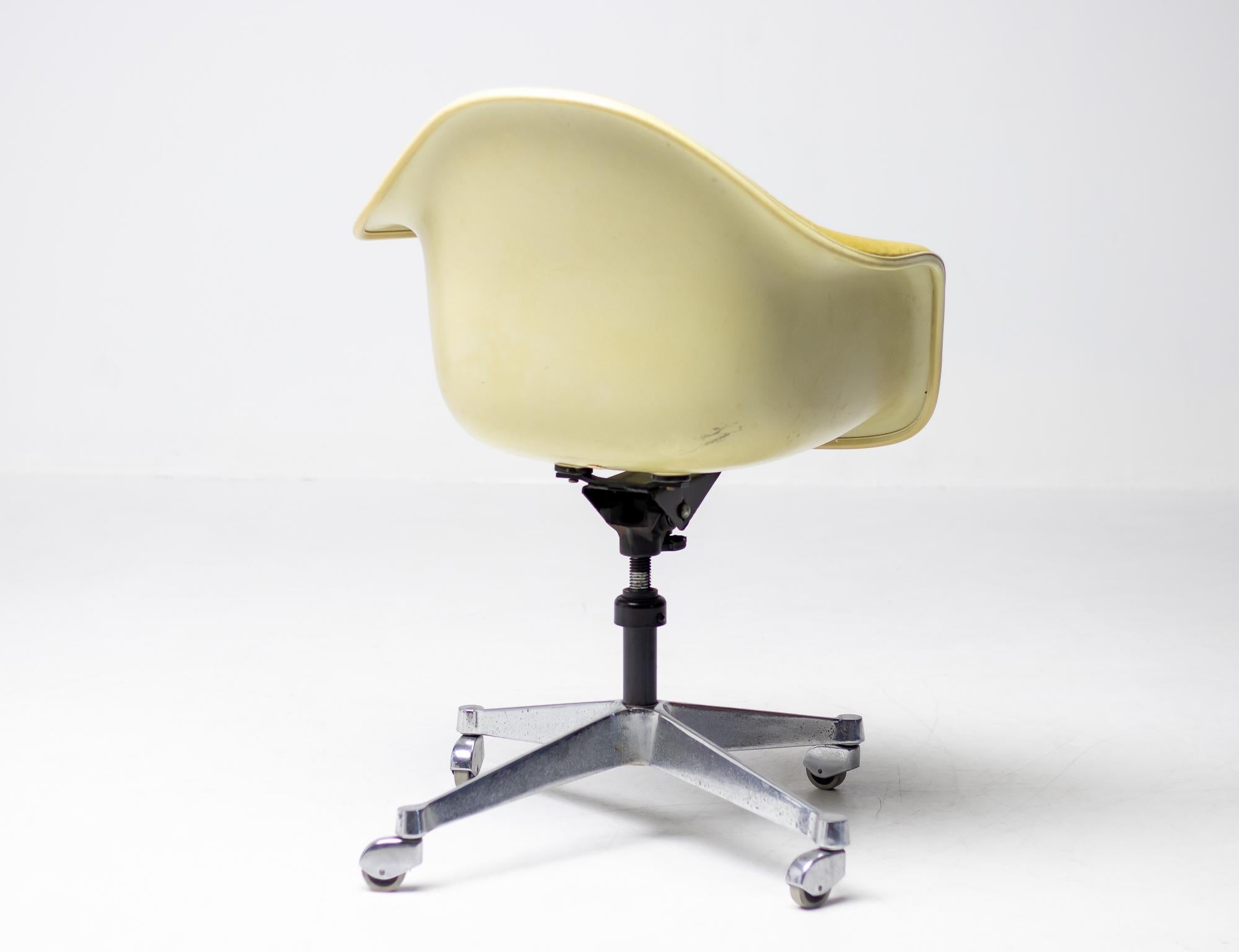 Classic Charles & Ray Eames height adjustable desk chair on castors with tilt and swivel with a fiberglass armshell on a chrome base. The armshell is upholstered in yellow fabric. Tilt, swivel and height adjustment are fully functional.
     