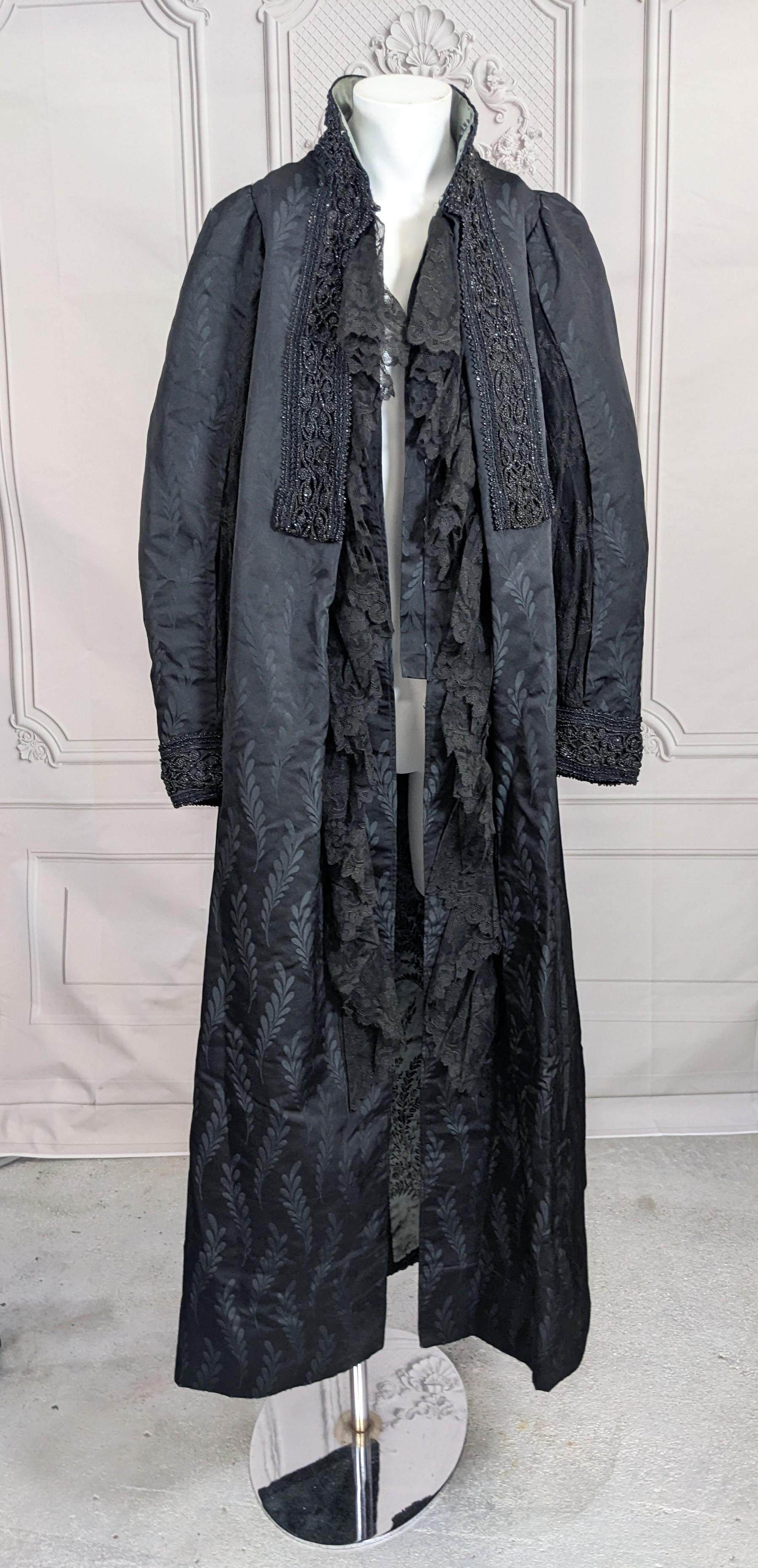 Schöner Maison Worth by Charles Frederick Worth Schwarzer Satinbrokatmantel aus dem späten 19. Jahrhundert. 
Amazing Silk Satin Brokat von Farnen mit Spitzeneinsätzen in den Ärmeln. Spitzenrüschen fallen vorne kaskadenförmig herunter und werden mit