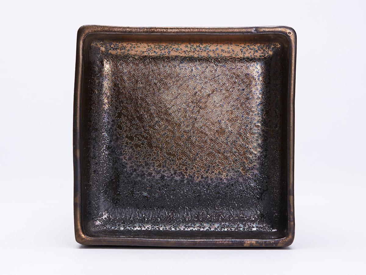 Un élégant plat en grès lustré de forme carrée peu profonde, en poterie d'art Greber française, reposant sur un pied non émaillé à glaçures métalliques oxydées. Fabriqué à Beauvais et probablement par Charles Greber (1853-1935), le plat est marqué