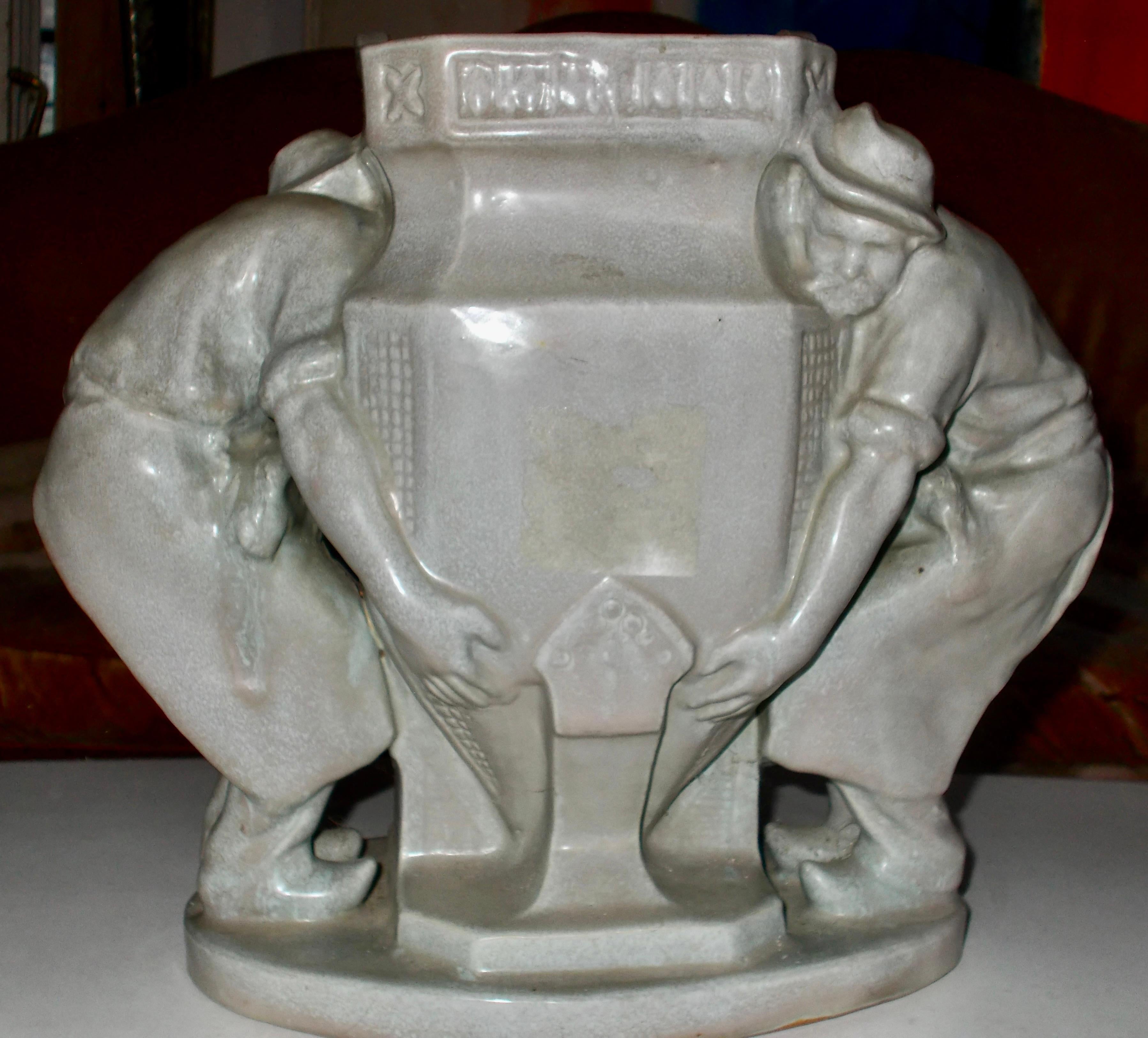 A large grey glazed stoneware ceramic by the French Sculptor Charles Greber (1853-1935), of two workmen moving a large jardiniere. Signed: Charles Greber Beauvais.