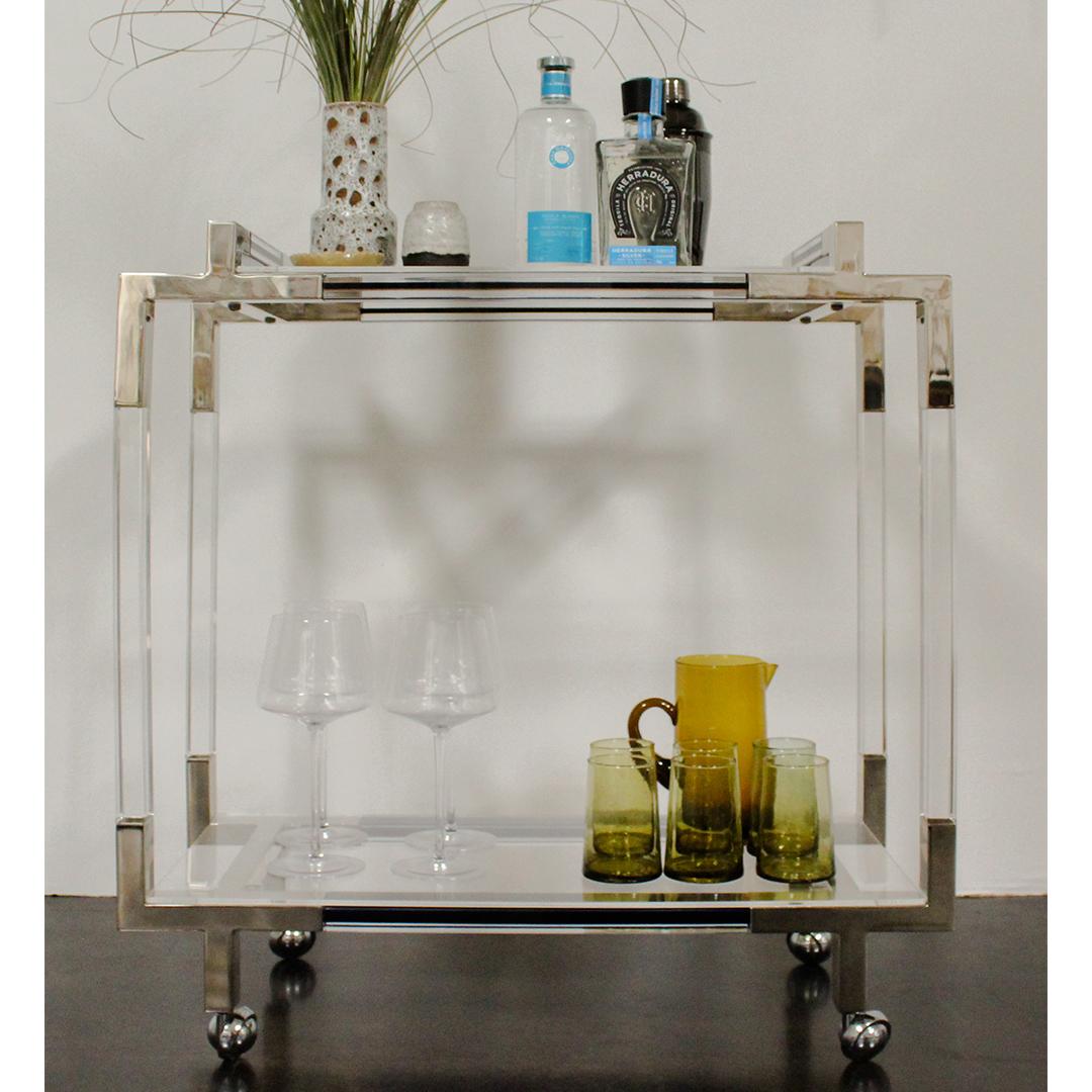 An original lucite and chrome bar cart by Charles Hollis Jones with cobalt blue colored accent sides and handles. On castors for easy movement with a top and bottom lucite shelves.

About Charles Hollis
Born in 1945 in Indiana and moved to Los