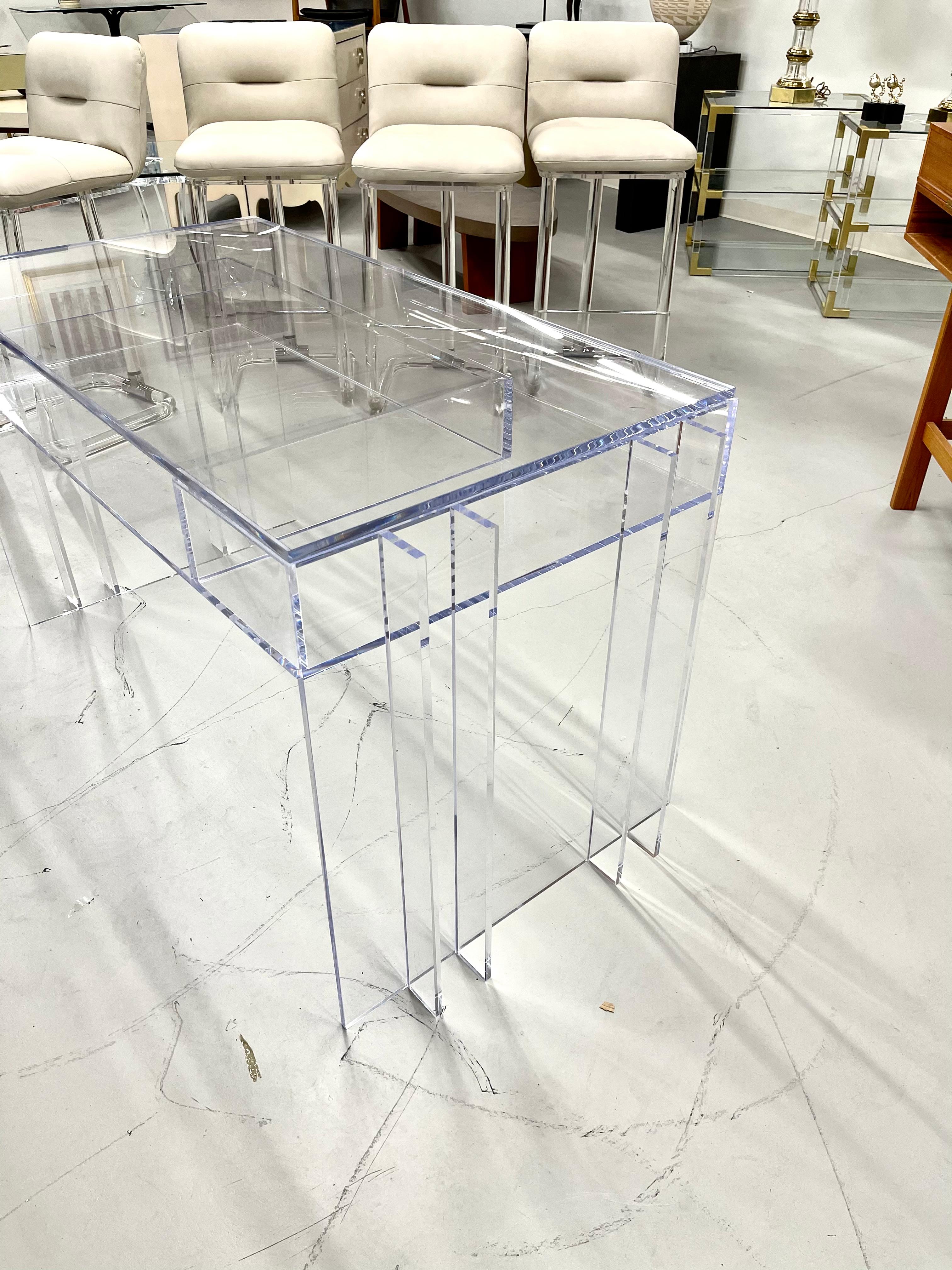 A beautiful blade line Lucite desk by Charles Hollis Jones. Has 3 compartments in the front and has a drop in piece of lucite for the top. It is 54 by 26 inches in dimension and 29 1/2 inches tall. It is a current production piece, but this piece is