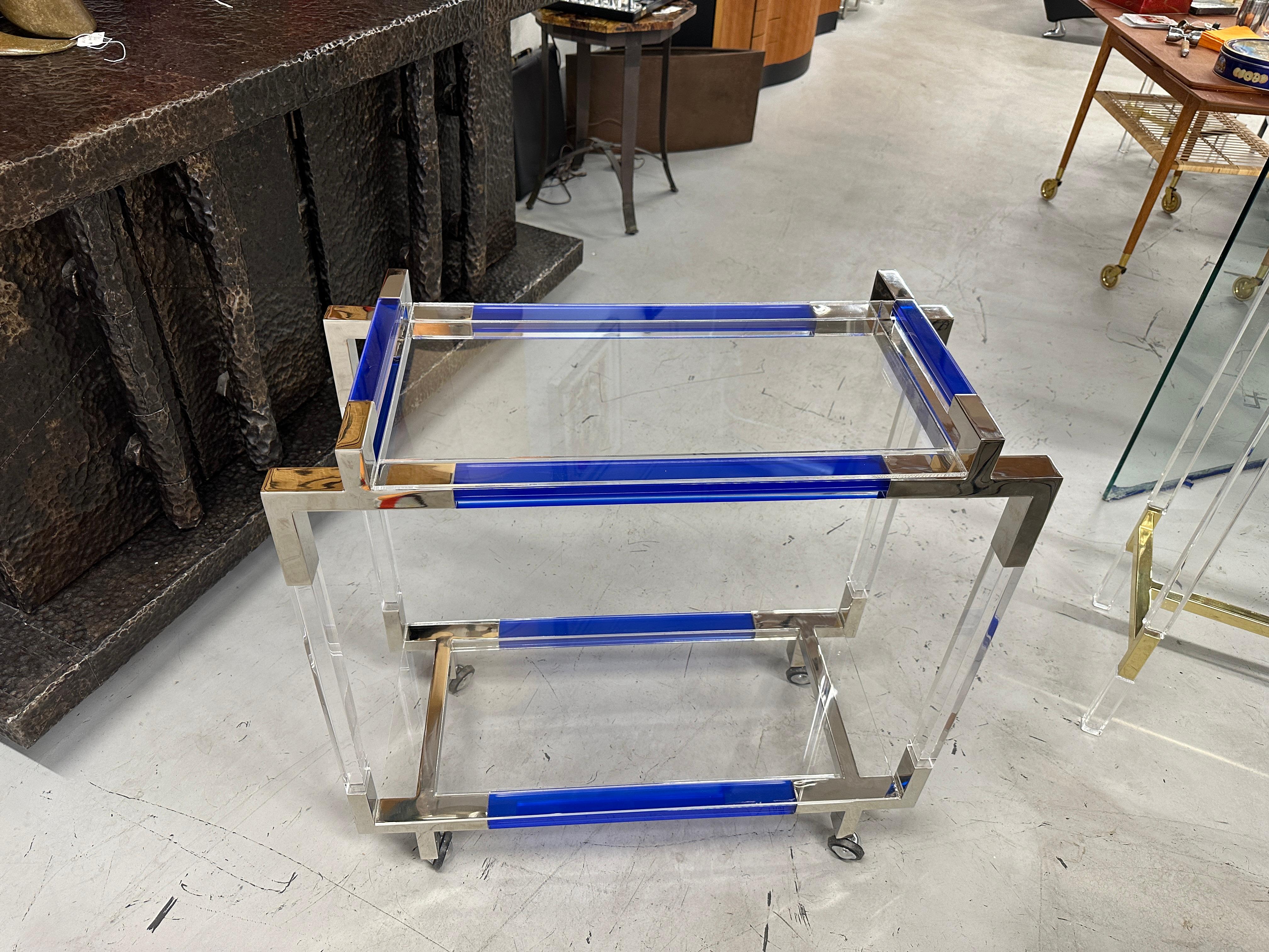 A lovely Charles Hollis Jones bar cart with Cobalt blue colored accent sides and handles. On rubber trimmed castors for easy movement. The top and bottom shelf are lucite. The trim is polished nickel.
Purchased directly from Mr. Jones.
It is