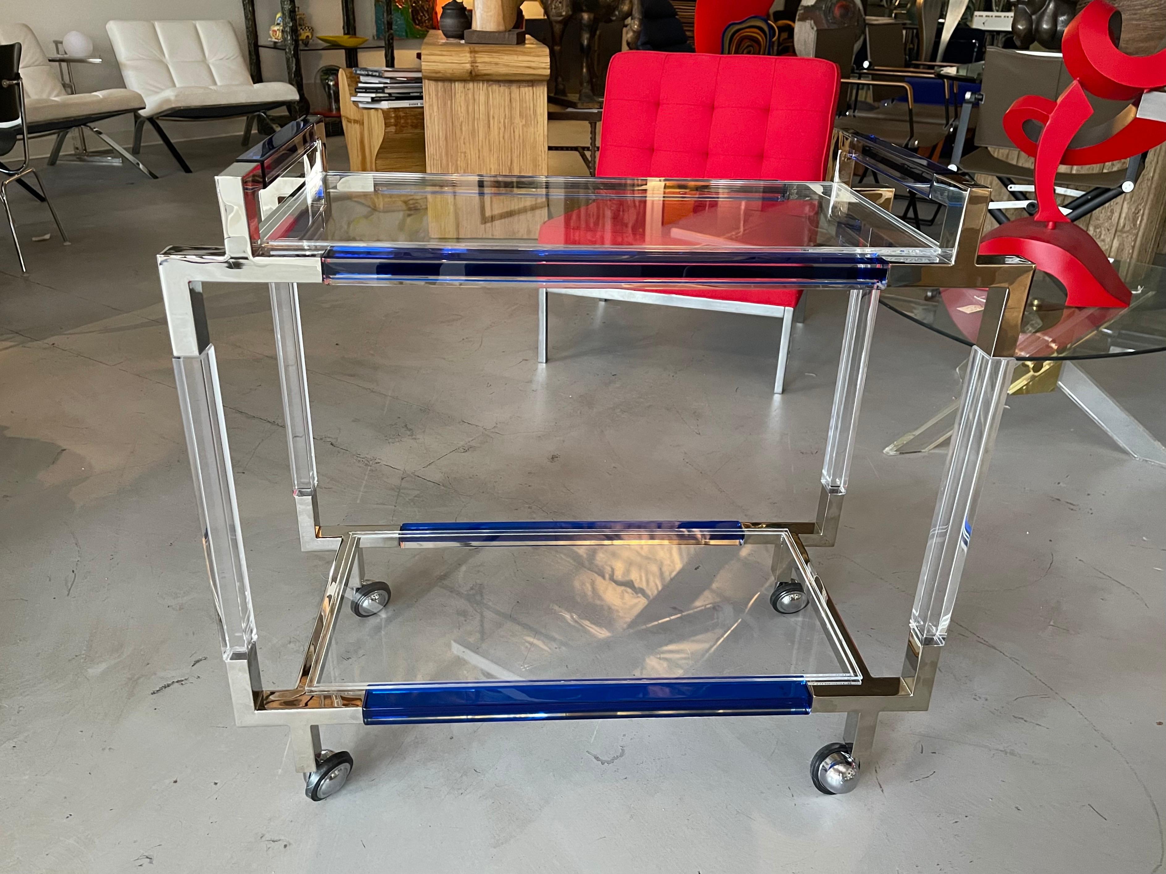 A lovely Charles Hollis Jones bar cart with Cobalt blue colored accent sides and handles. On castors for easy movement. The top and bottom shelf are lucite. The trim is polished nickel.