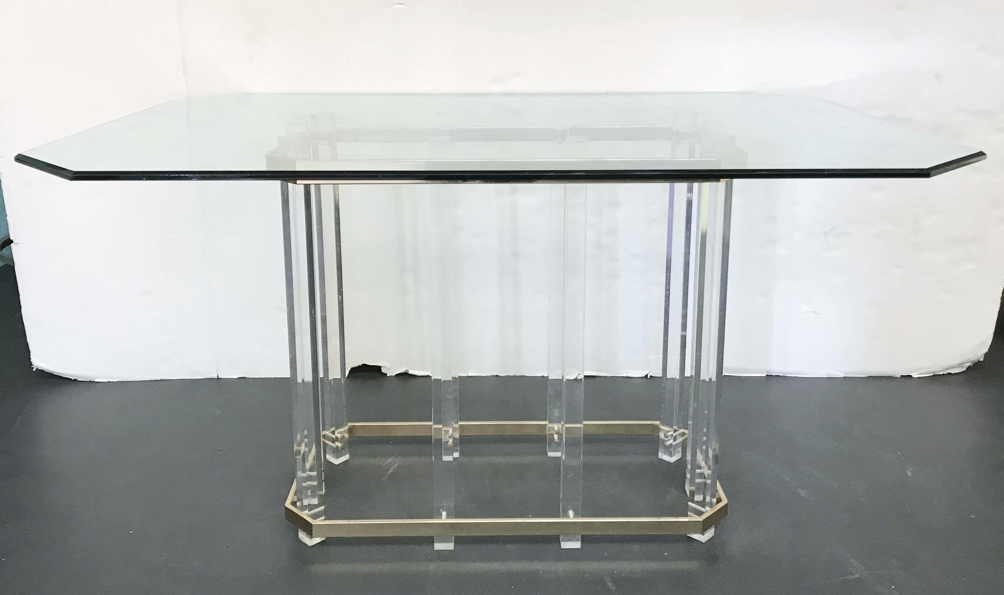 Vintage midcentury dining table with ten acrylic Lucite pillars wrapped around by two polished brass bars supporting a large geometric beveled glass top mimicking the form of the table base, designed by Charles Hollis Jones, made in the USA, circa