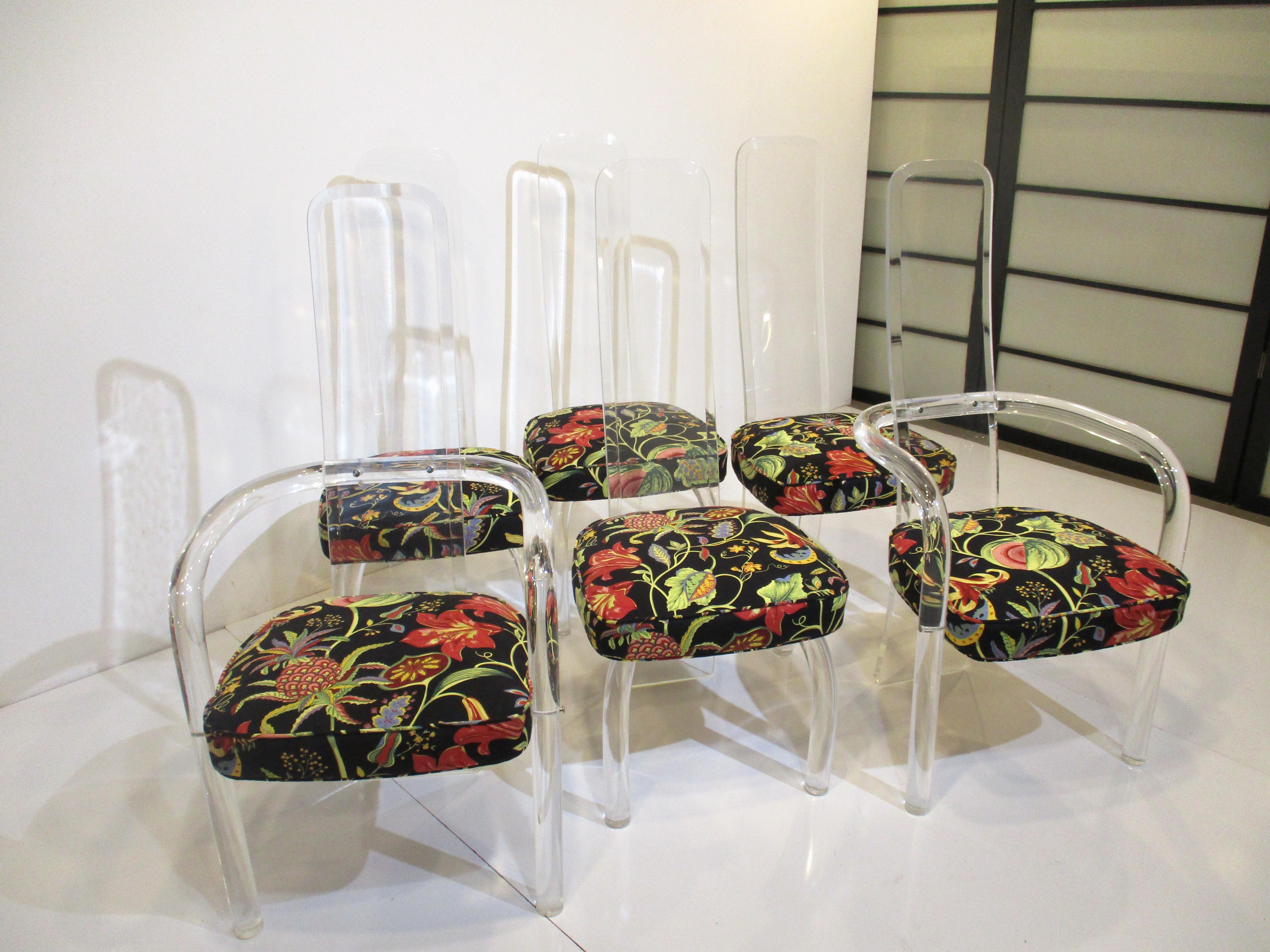 A set of six high back Lucite dining chairs with four side chairs and two chairs having sculptural arms . The back forms the back leg structure and is detailed with chrome studs at the screw points all with high quality multi colored fabric seat