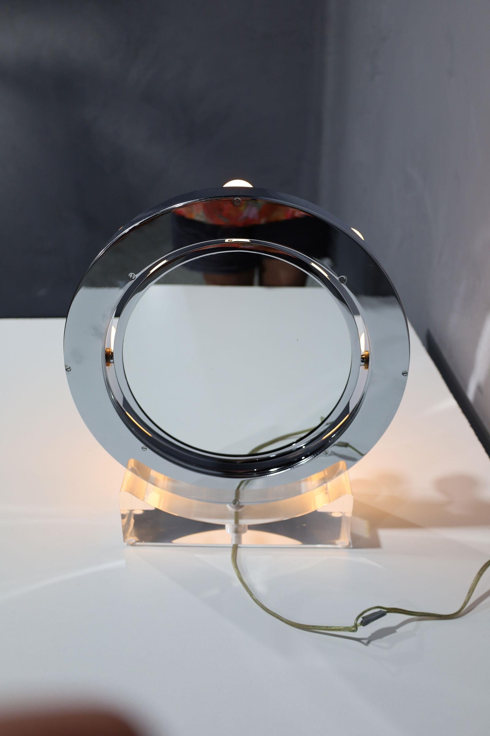 Stunning and rare makeup mirror designed and manufactured by Charles Hollis Jones in the early 1970s.
The mirror has lights all around and it has a flip mechanism, one side has a regular mirror and the opposite side has a magnifying mirror.

The