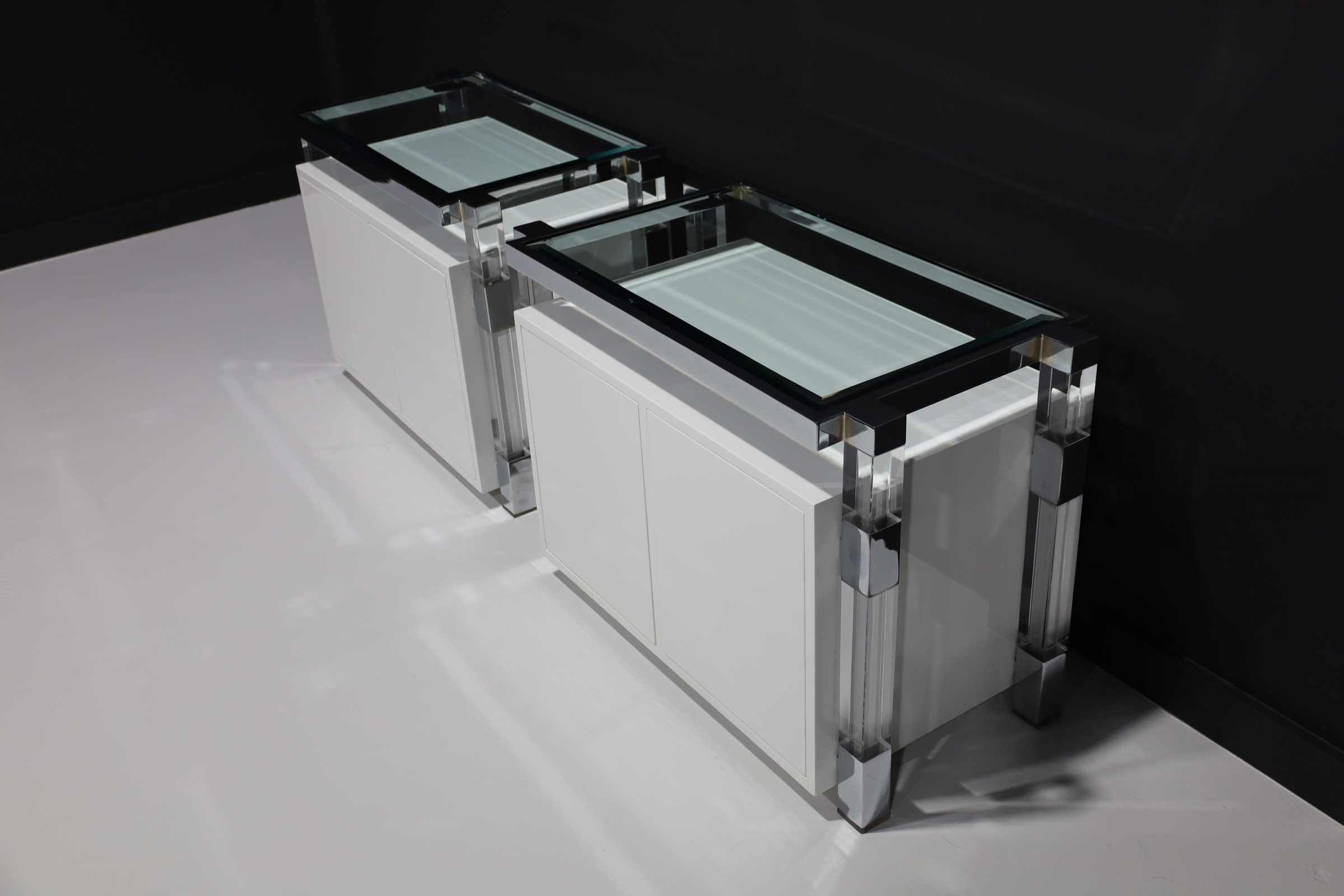 Beautifully restored pair of nightstands by Charles Hollis Jones. Chrome and Lucite Frames, floating white lacquer case piece, two push button doors opening opposite on either side of bed for easy access.