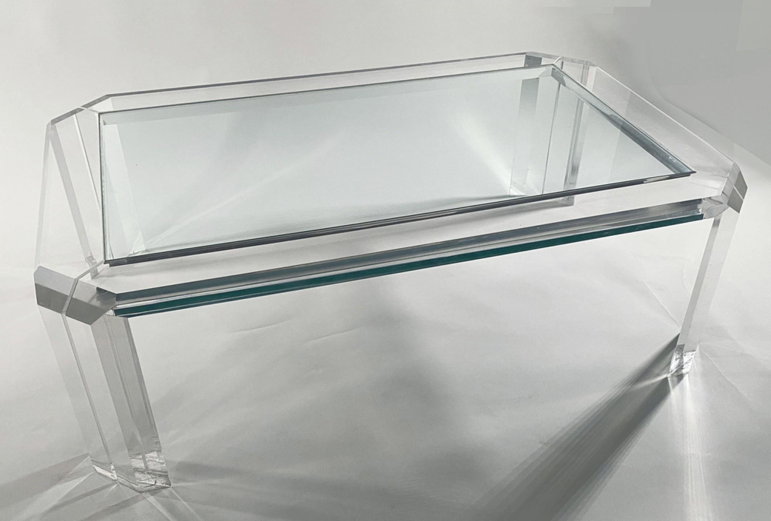 Midcentury American Modern rectangular lucite frame cocktail / coffee table with an inset clear glass top and canted corners, resting on four tapered lucite legs. (Charles Hollis Jones).