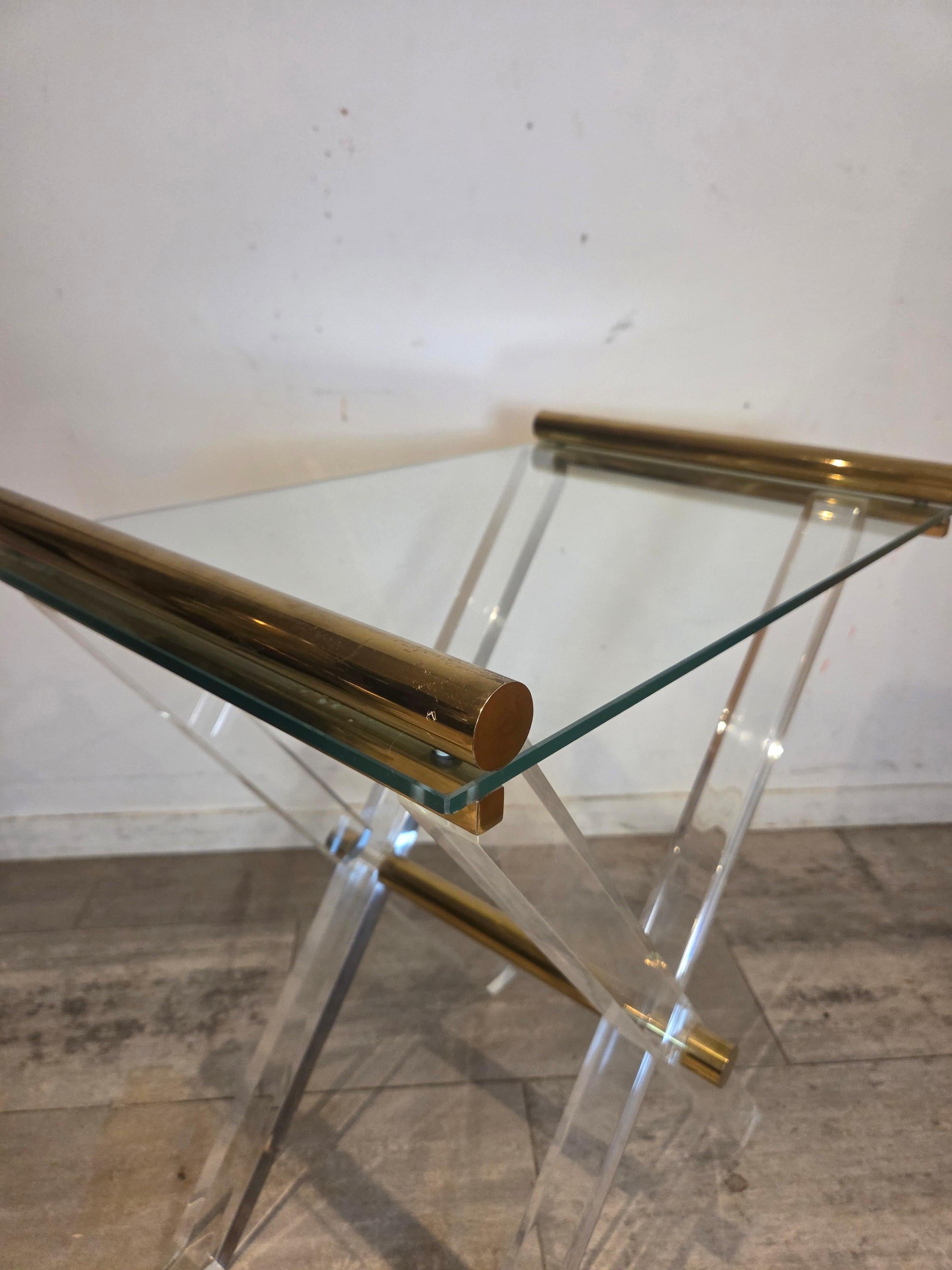 Elegante mesa auxiliar del legendario diseñador Charles Hollis Jones, con patas de Lucite transparente, detalles de latón pulido y tapa de cristal. Un asombroso ejemplo del estilo de la Regencia de Hollywood de los años setenta: llamativo,