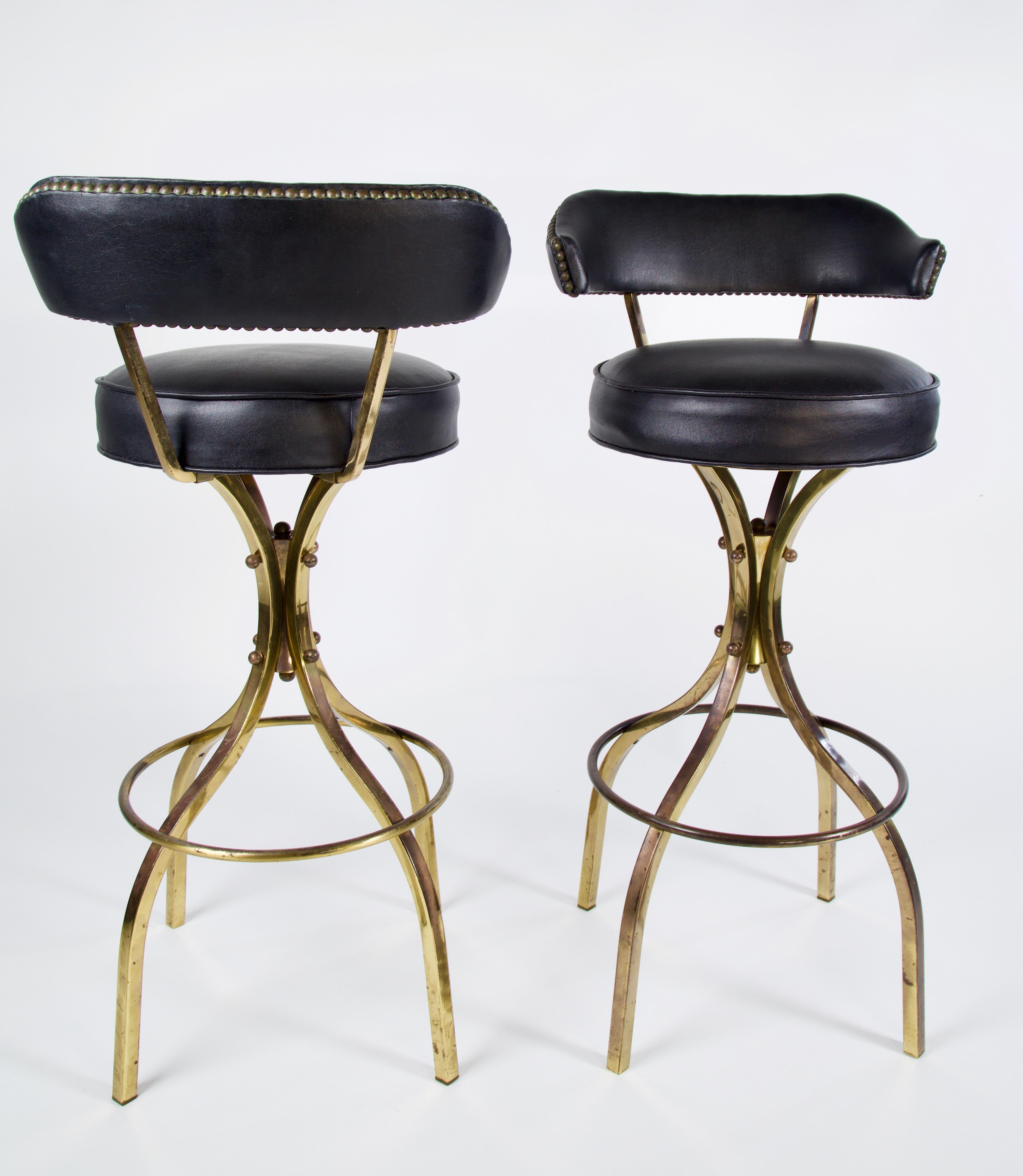 These sexy Charles Hollis Jones Sinatra bar stools are in original condition with a swivel seat upholstered in black Naugahyde and patinaed brass legs . Brass can be polished if desired. These are highly collected and sought after vintage Charles