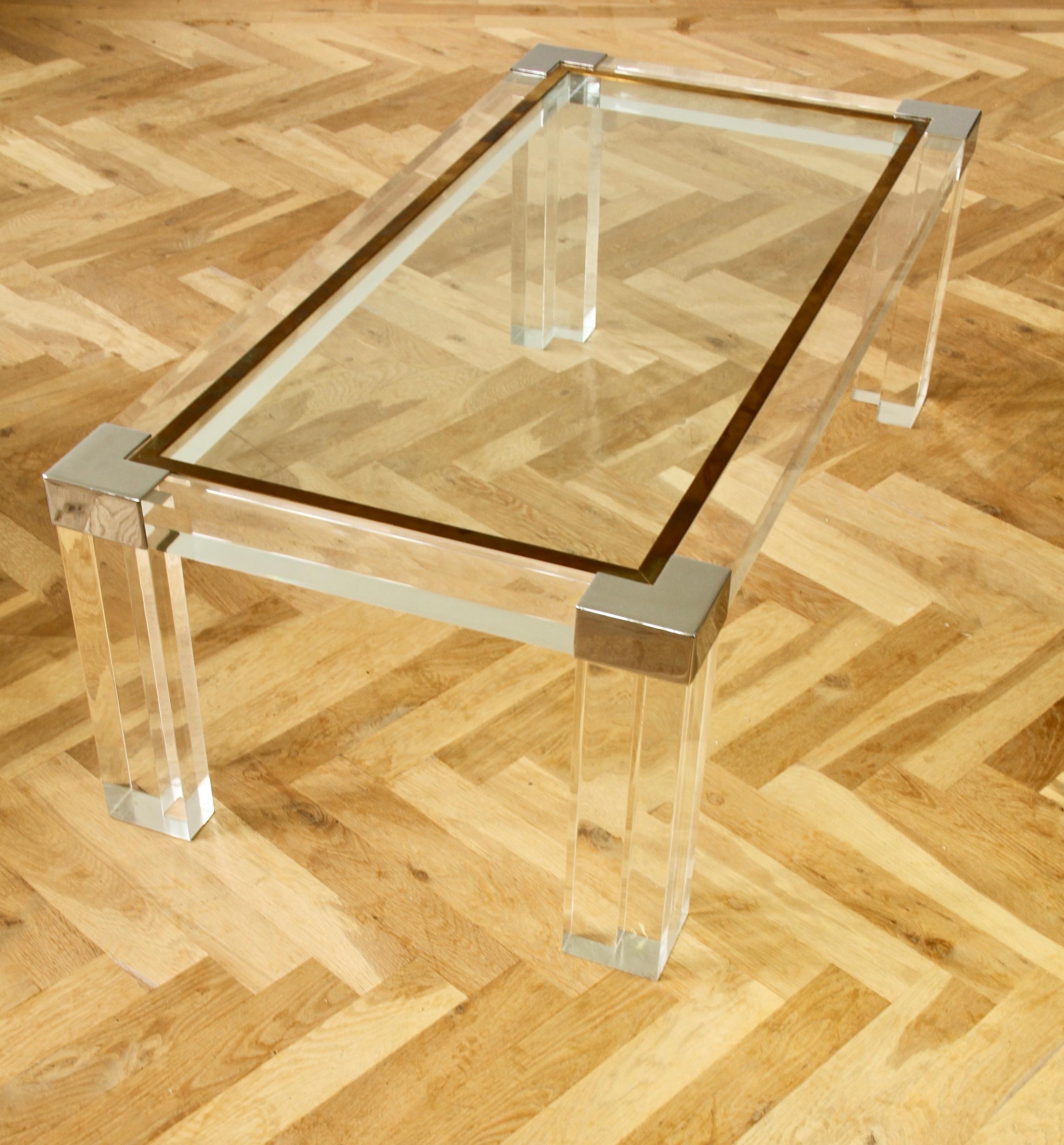 Charles Hollis Jones style rectangular coffee or center table made of Lucite / acrylic with glass tabletop with brass trim and chrome corners. The heavy and thick Lucite legs and frame hold the glass tabletop which has a wonderful patina to the