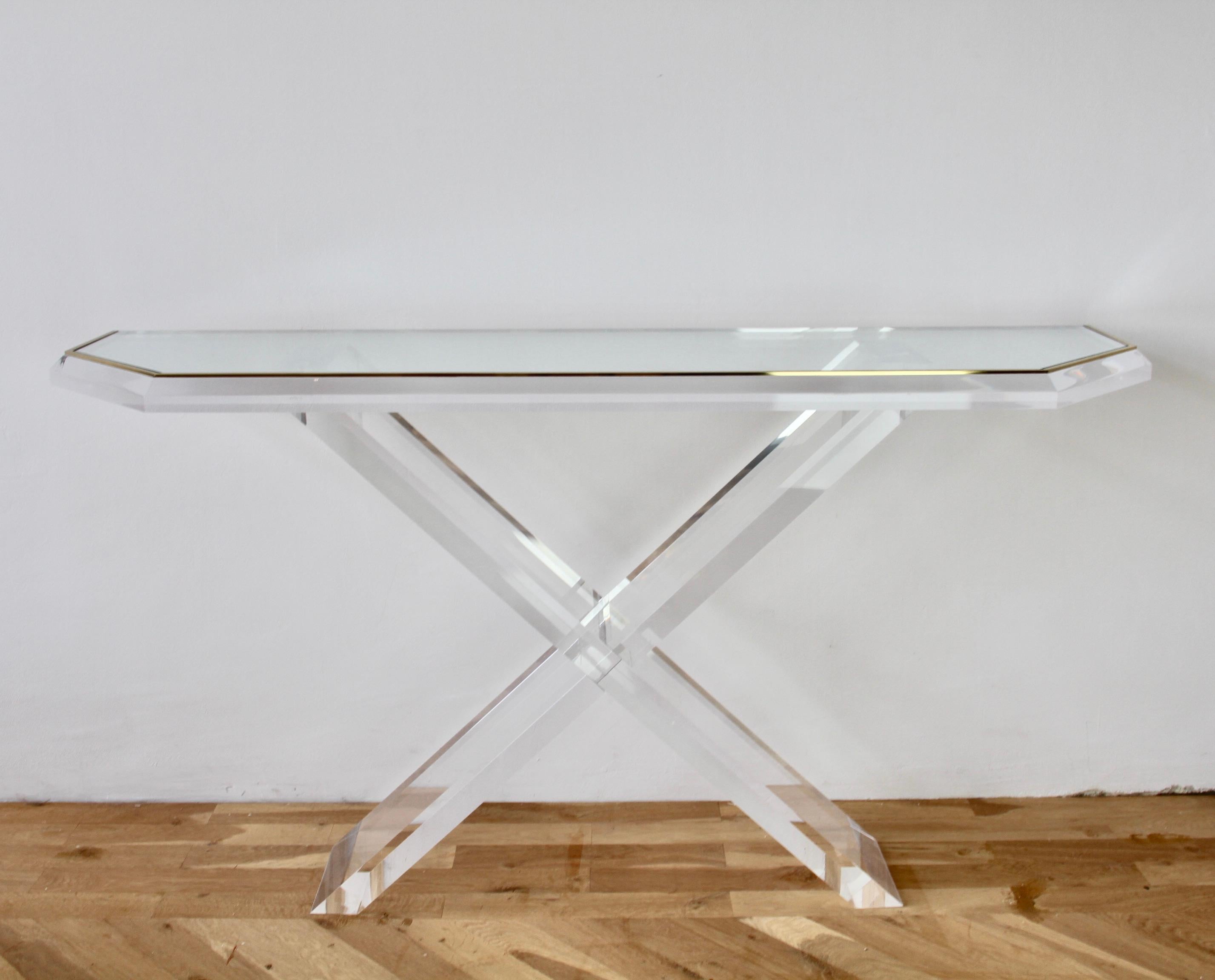 Charles Hollis Jones style huge five foot long (149.5cm) console, foyer or entrance table made of Lucite / acrylic with glass tabletop with brass trim and angled corners, circa 1980s. The heavy and thick Lucite legs and X-base frame hold the glass
