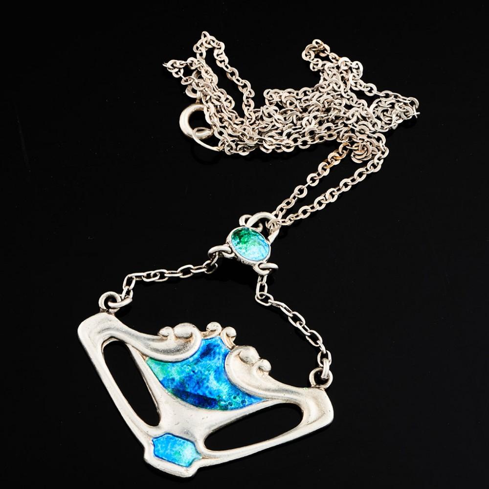 Heading : Charles Horner Arts and Crafts silver and enamel pendant
Date : Hallmarked in Chester in 1909 for Charles Horner
Period : Edward VII
Origin : Chester, England
Decoration : Open whiplash tendril shield with blue green enamel suspended on