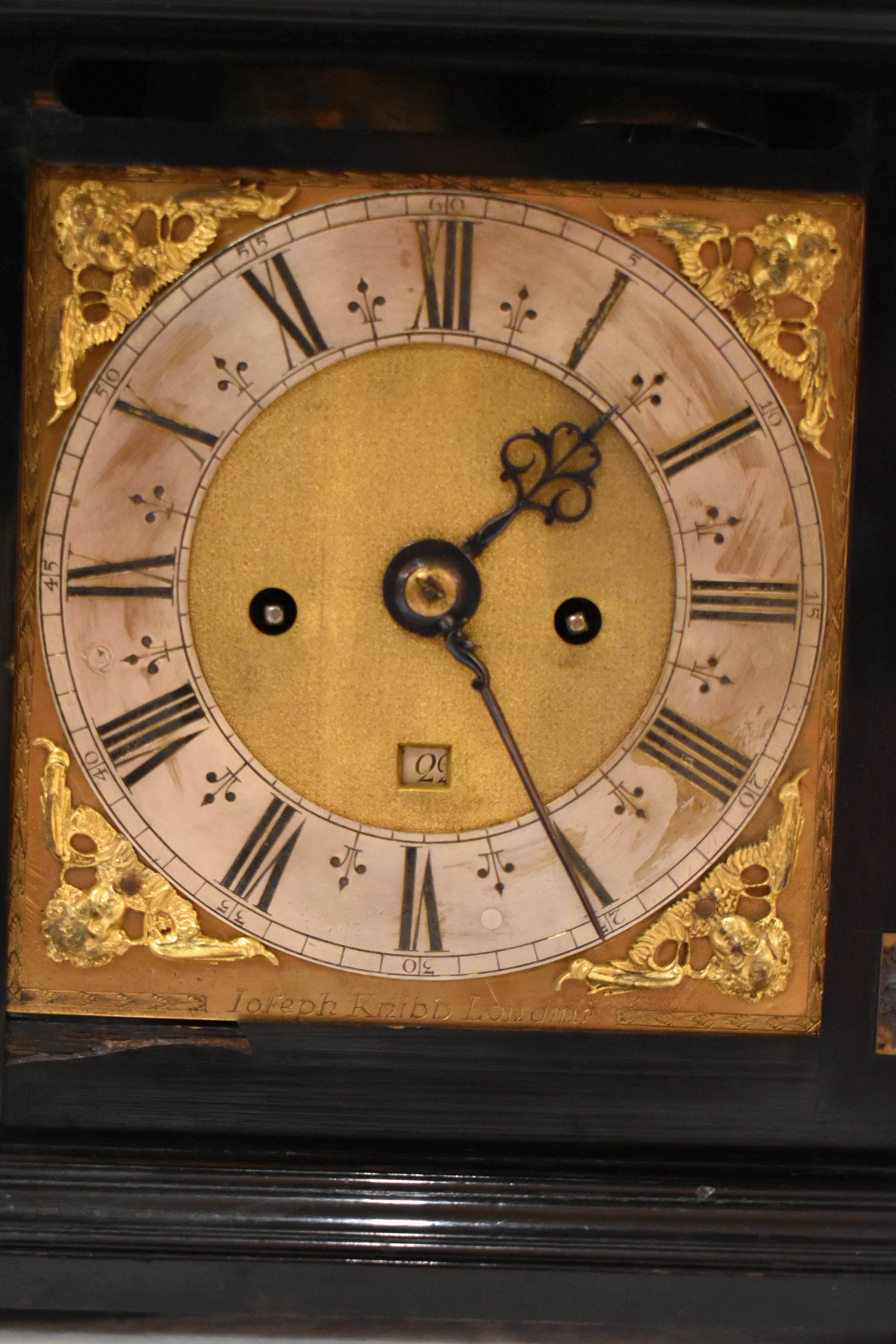 An 8-day ebony table clock with dial plate inscribed JOSEPH KNIBB LONDON and back plate inscribed JOSEPH KNIBB LONDON FECIT.

The ebony veneered case is surmounted by a foliate tied handle with turned base plates above the cushion molded top with