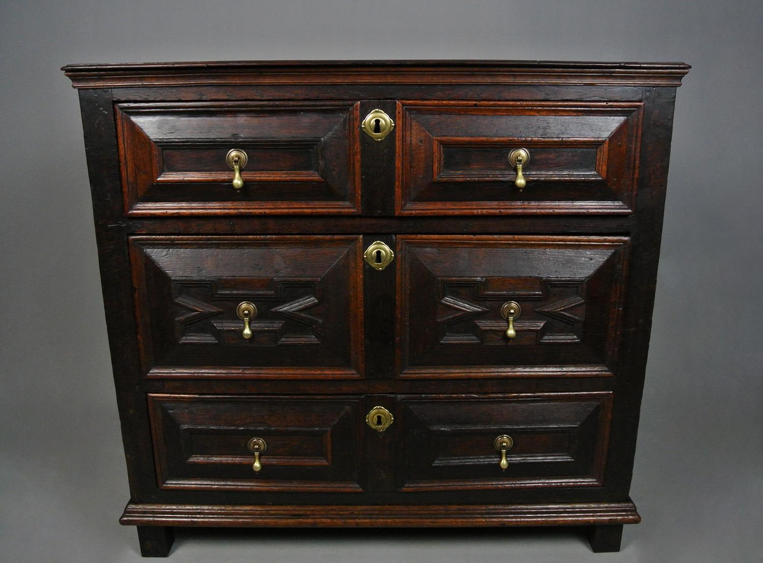 A really good and original solid oak 17th Century English chest of drawers with bolection moulded drawers and original hand cast brass drop handles. The three long drawers with rebated runners and retaining their original linings of substantial oak