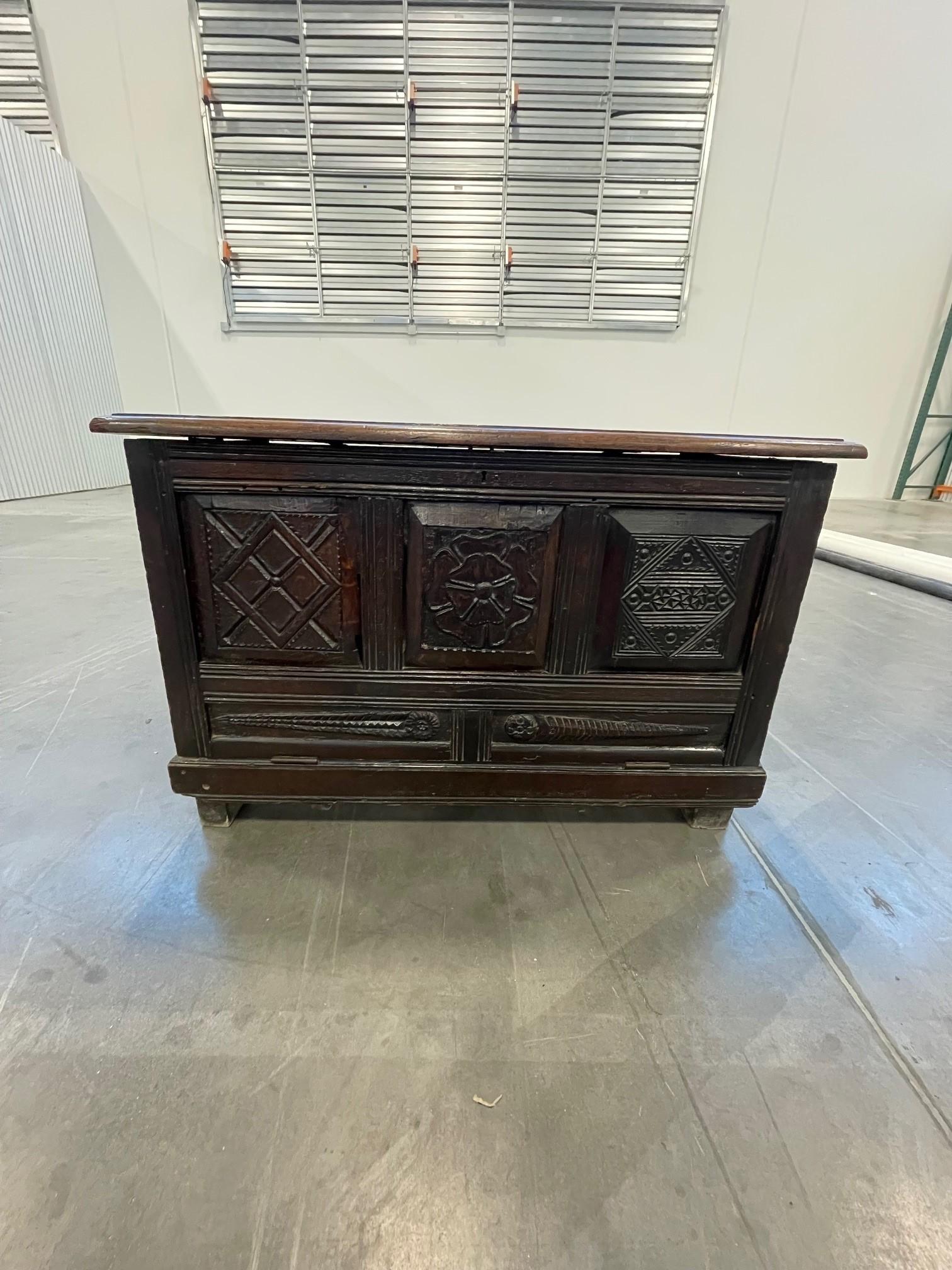A 17th century oak coffer, that has later been converted to a fall front blanket chest, the rectangular molded top above three panels carved with individual motifs, upon stile feet, 27