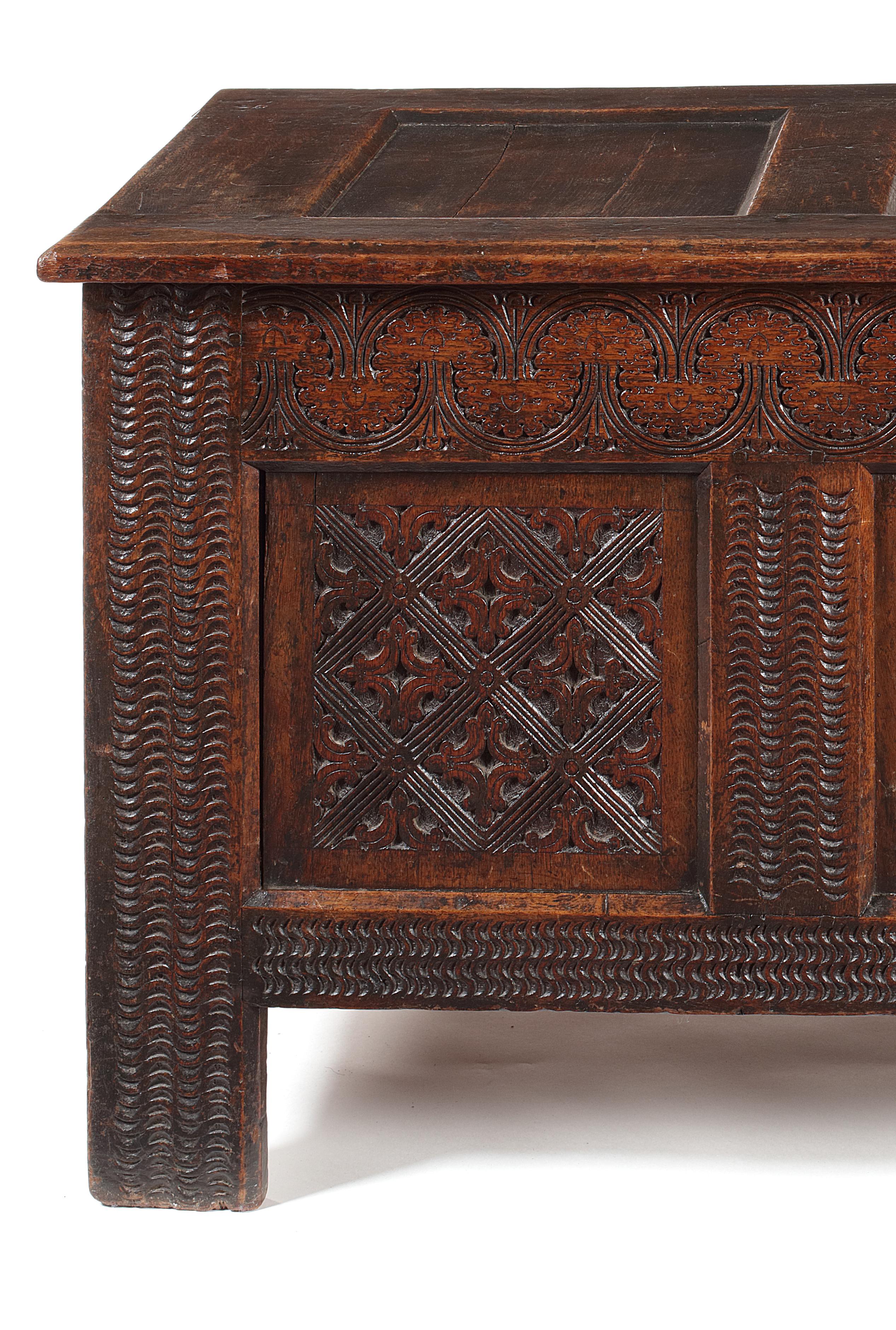 The three-panel lid above a profusely carved three-panel front with low relief interlocking foliate motif to the frieze, each panel with a lattice design flanked by uprights and stiles with wavy gouge-carved detail. Measures: 131cm wide, 51cm deep,