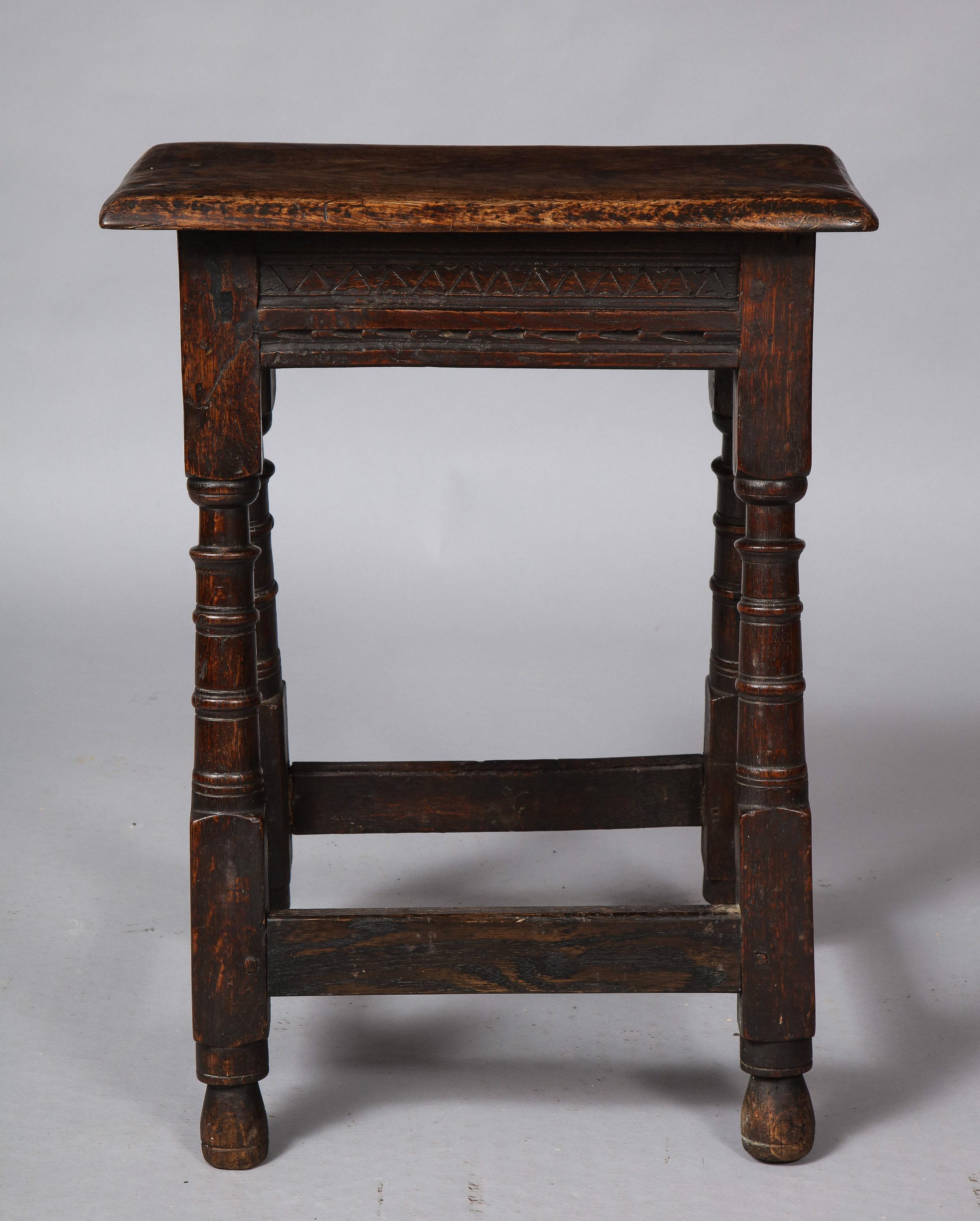 Fine English 17th century joint stool, the single plank oak top over carved aprons and unusual turned legs joined by box stretchers and standing on original turned feet, the whole with great color and patination.