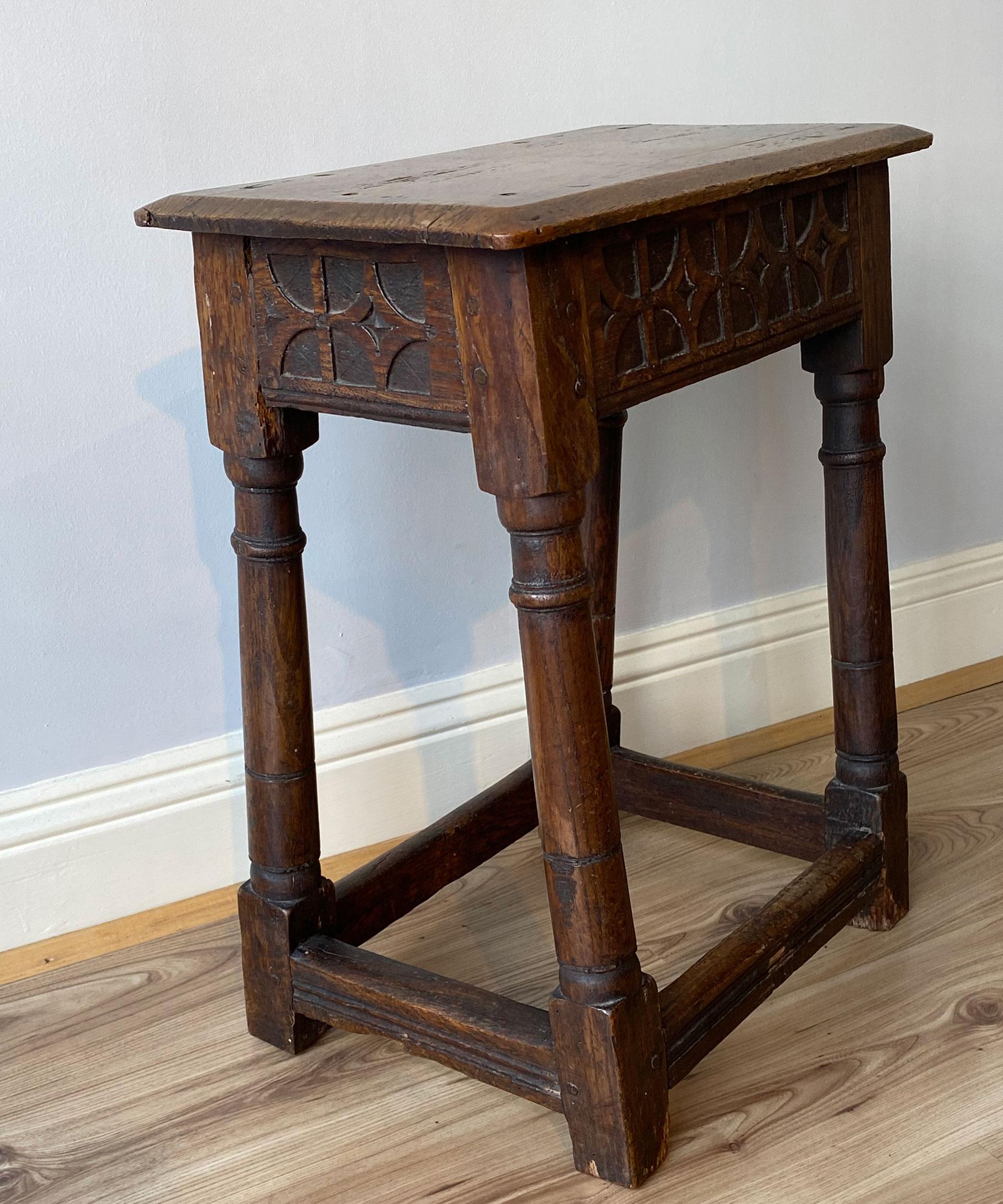 A Charles II carved oak joint stool; the stool's top with chamfered edges above a frieze boldly carved with quatrefoils, raised on ring turned legs united by moulded stretchers.

 