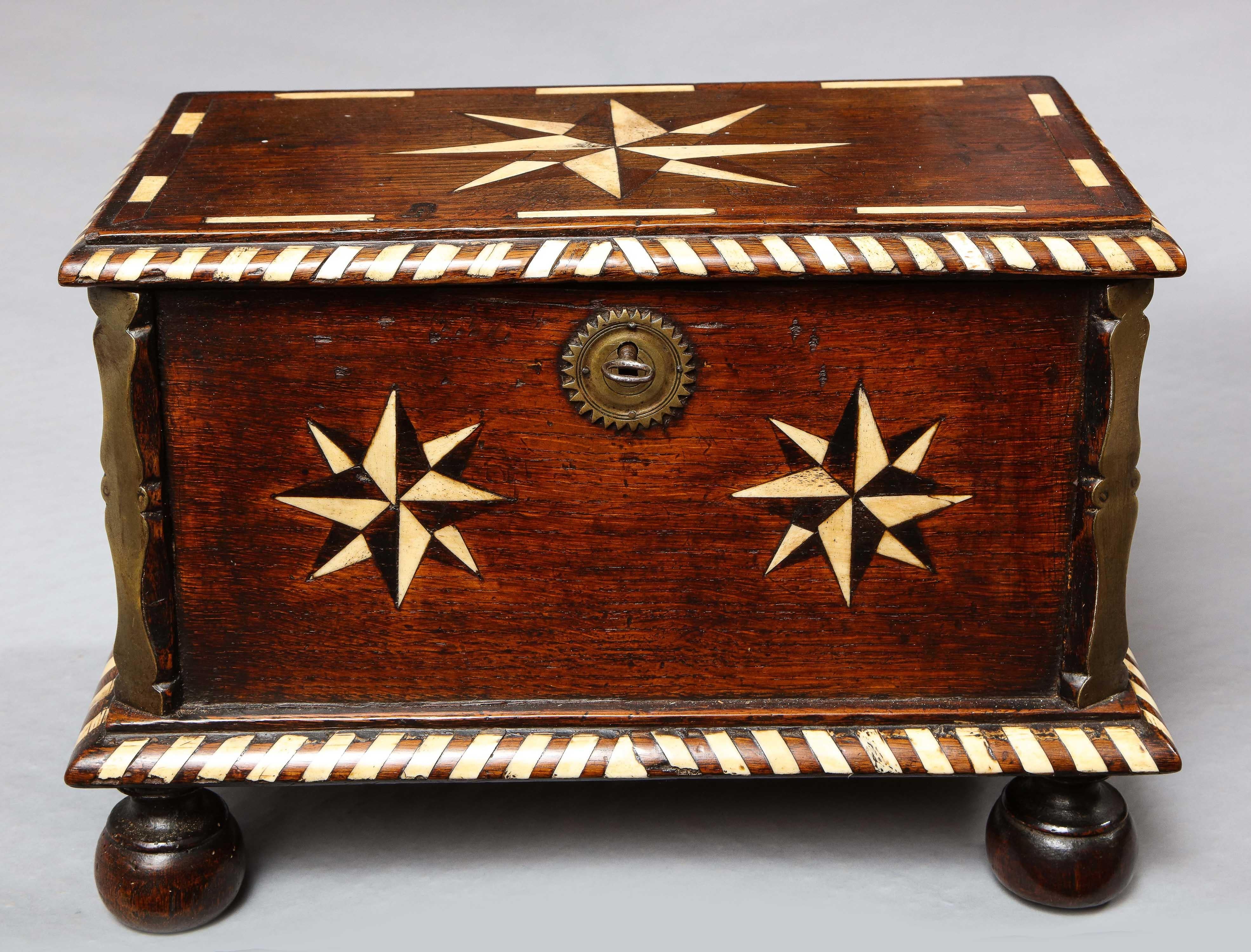 Rare mid-17th century English bone inlaid and brass mounted oak center table box, the top and sides inlaid with compass stars in bone and ebonized fruit-wood, the edges with bone and oak inlaid gadrooning, the corners mounted with double balustrade