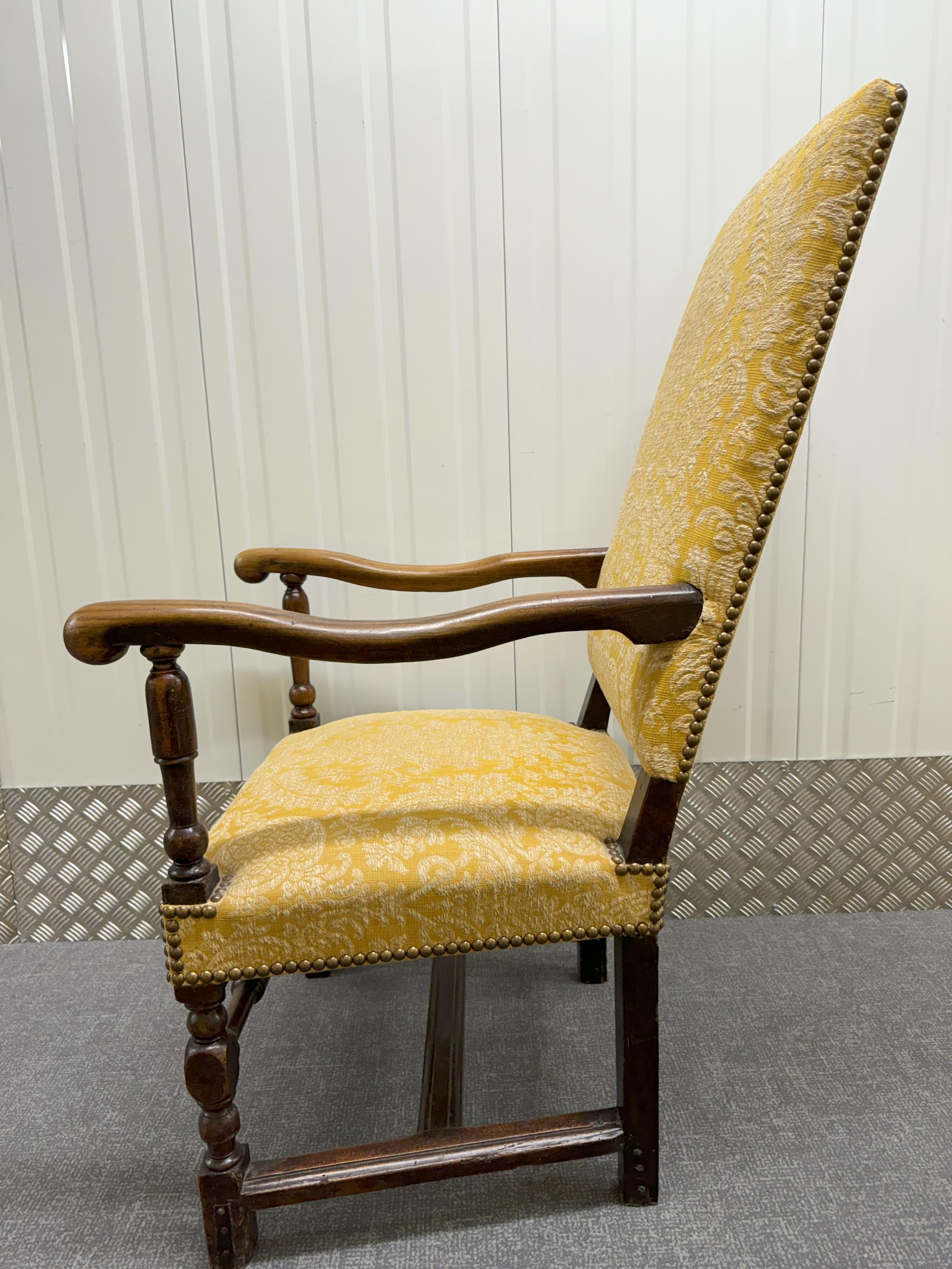A Charles II walnut elbow chair with foliate carved scrolling arms. The rectangular back and seat covered in modern needlework authentically styled to the period.     