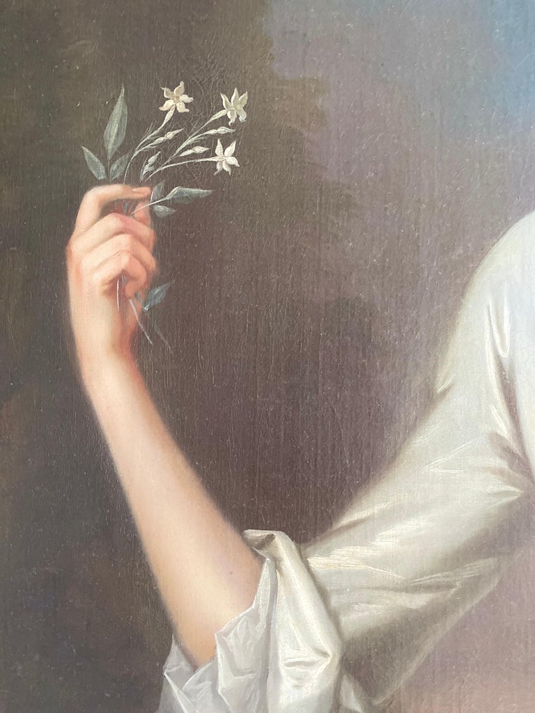 Portrait of Henrietta Pelham-Holles (née Godolphin) (1701-1776), Duchess of Newcastle, standing in a wooded landscape with a river beyond, three-quarter length wearing an ivory silk gown holding a sprig of flowers in her hand. Inscribed lower left