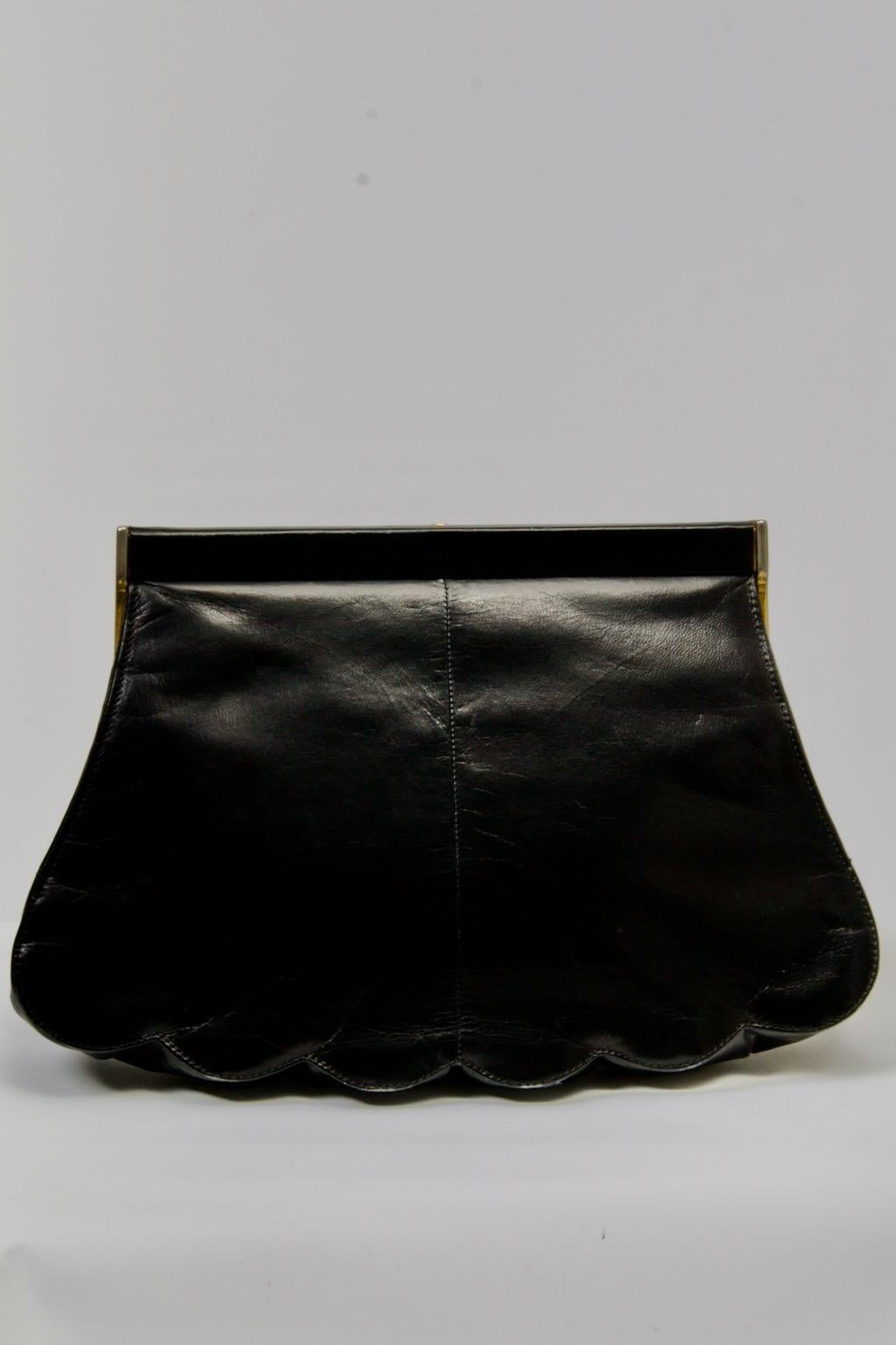 Charles Jourdan black leather clutch, c.1970s,  featuring a scalloped bottom and gold tone hardware with a turnkey lock. Black leather interior with zip compartment and rectangular gold tone tag marked 