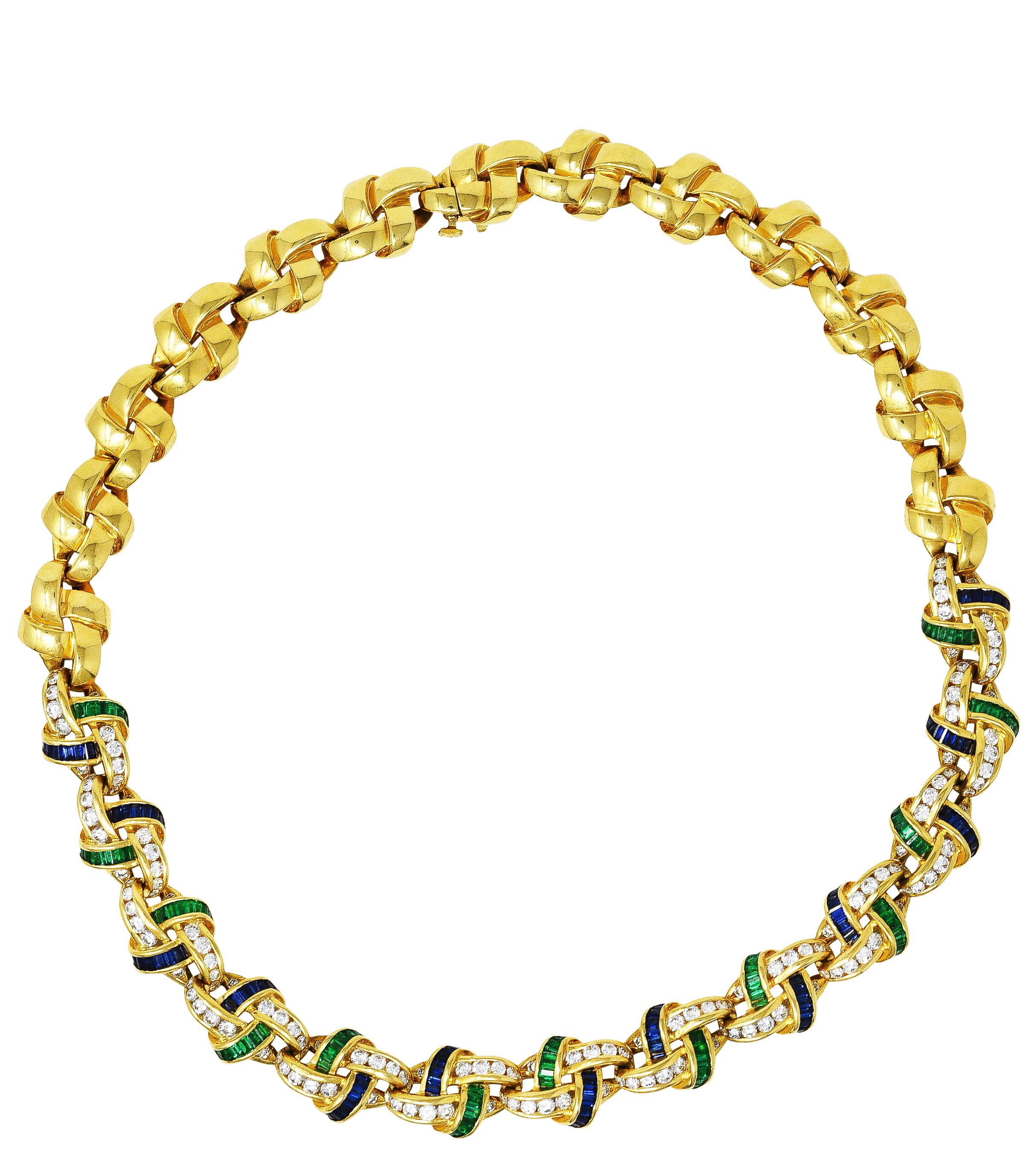 Collar necklace is comprised of polished gold knot motif links

Front facing links feature channel set emeralds, diamonds, and sapphires

Sapphires are a well matched royal blue color while weighing in total approximately 2.75 carats

Emeralds are