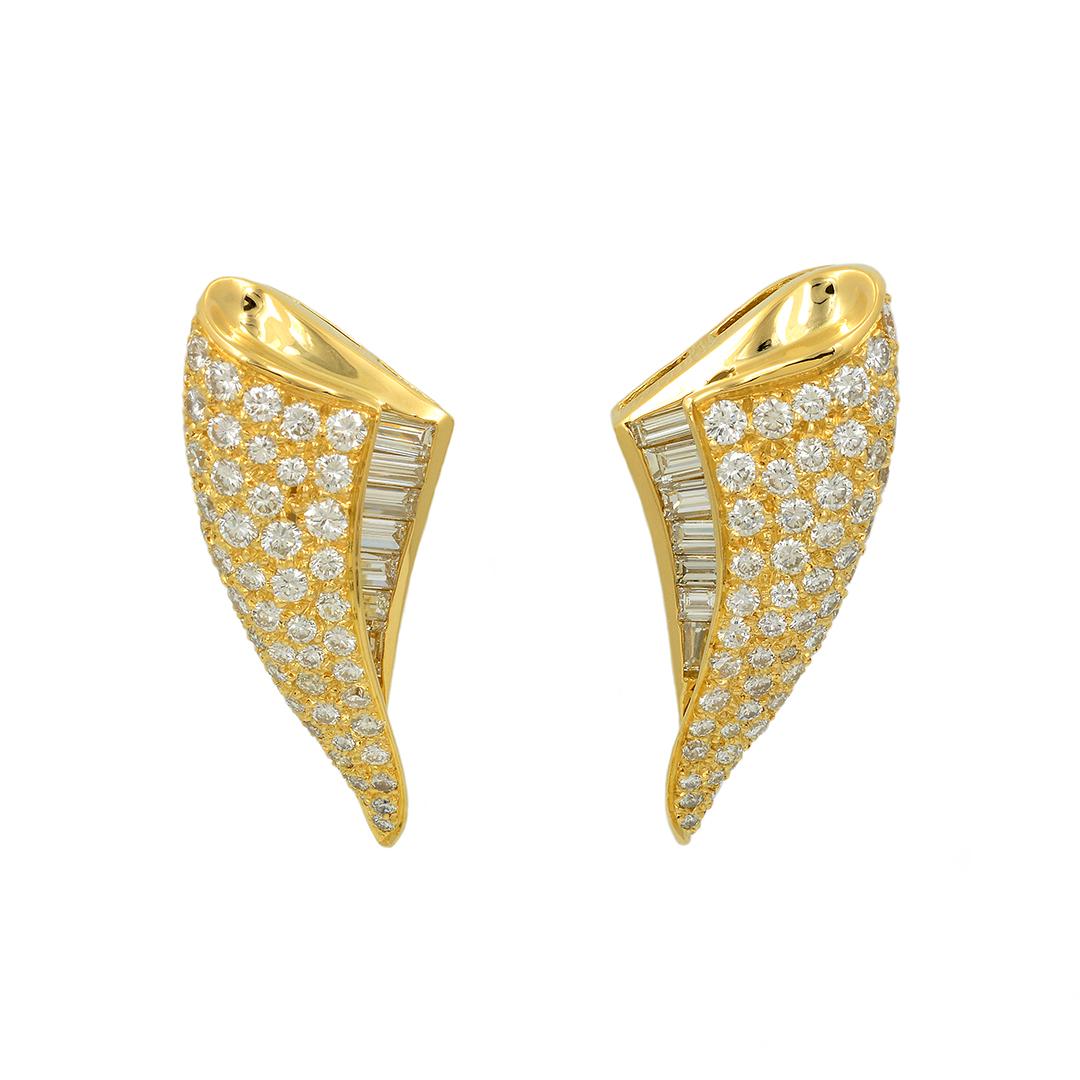 These 18 karat yellow gold clip earrings by Charles Krypell feature a unique wave shape with the top layer set with round brilliant cut diamonds and the bottom layer set with a row of graduated baguette diamonds, all weighing a combined approximate