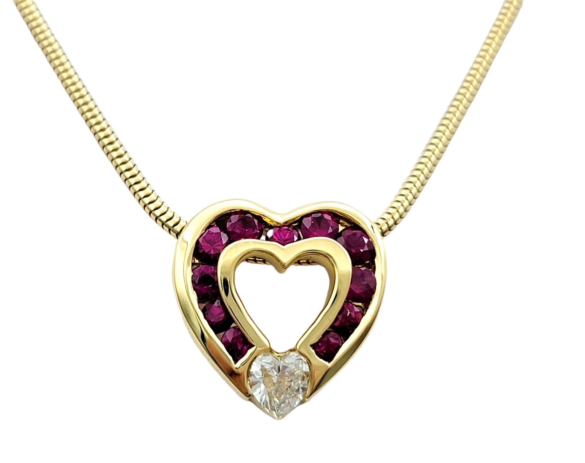 This Charles Krypell ruby and diamond open heart necklace is meticulously crafted in 18 karat yellow gold. Adorned with a striking contrast of rubies along the heart pendant's edge and a heart-shaped diamond nestled at its base, this necklace exudes