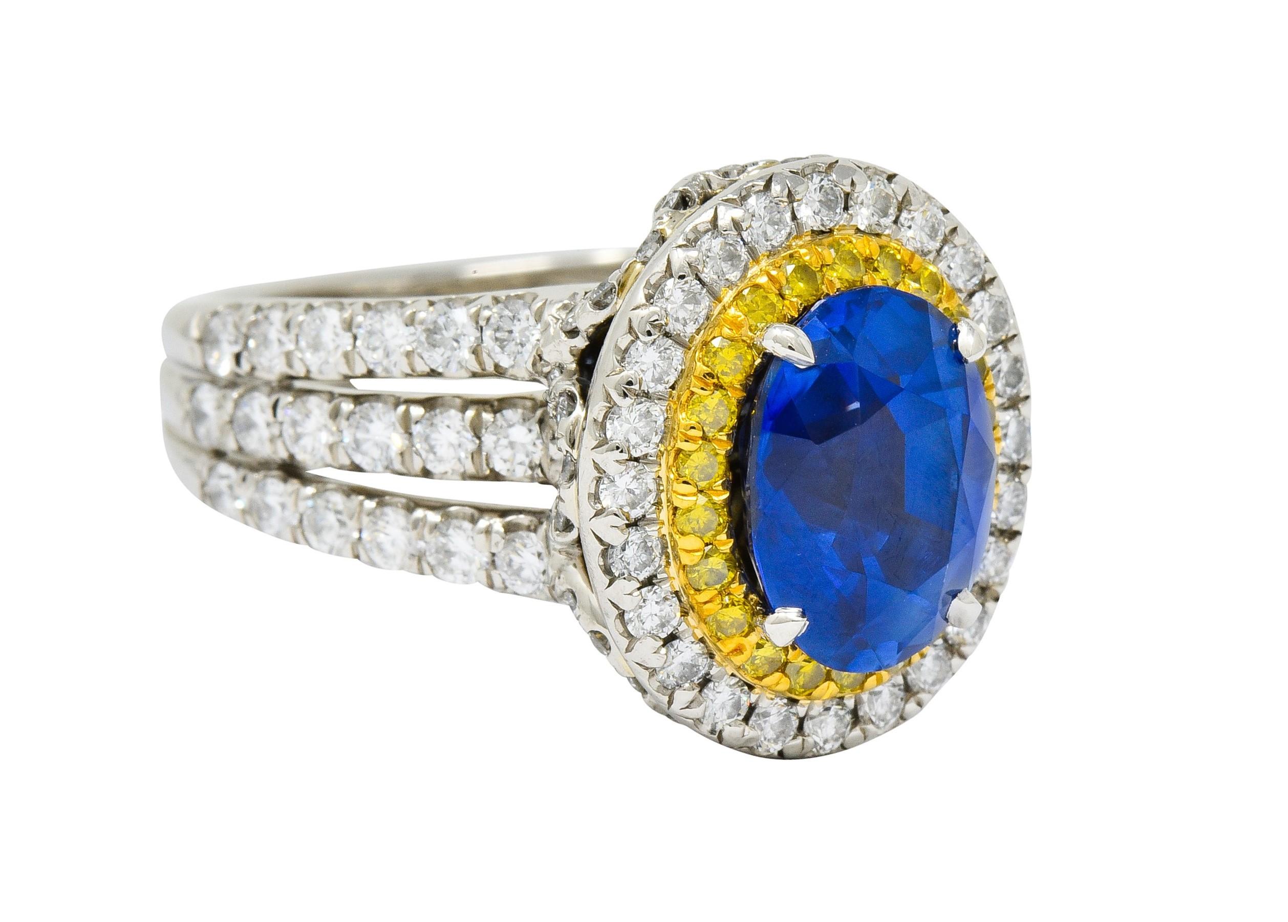 Centering an oval cut Ceylon sapphire weighing approximately 3.87 carats; bright blue in color with no indications of heat

Surrounded by a double halo of yellow and white diamonds, set in yellow gold and platinum

With a deeply scalloped gallery